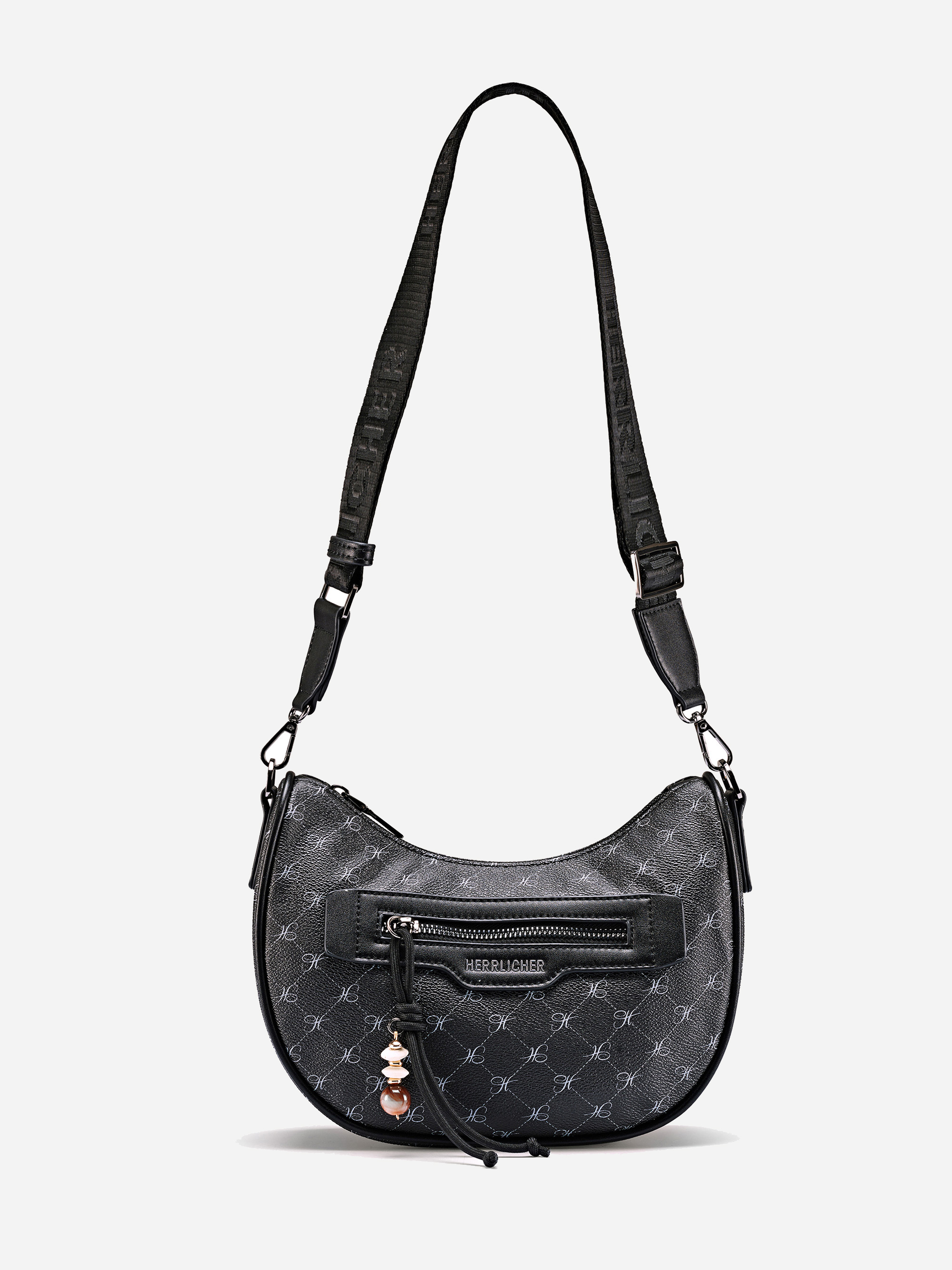 Schwarze Crossbody-Handtasche mit einem gemusterten Design, einer Reißverschlusstasche auf der Vorderseite und einem verstellbaren Schulterriemen. Die Tasche hat einen kleinen dekorativen Anhänger in der Nähe des Reißverschlusses.