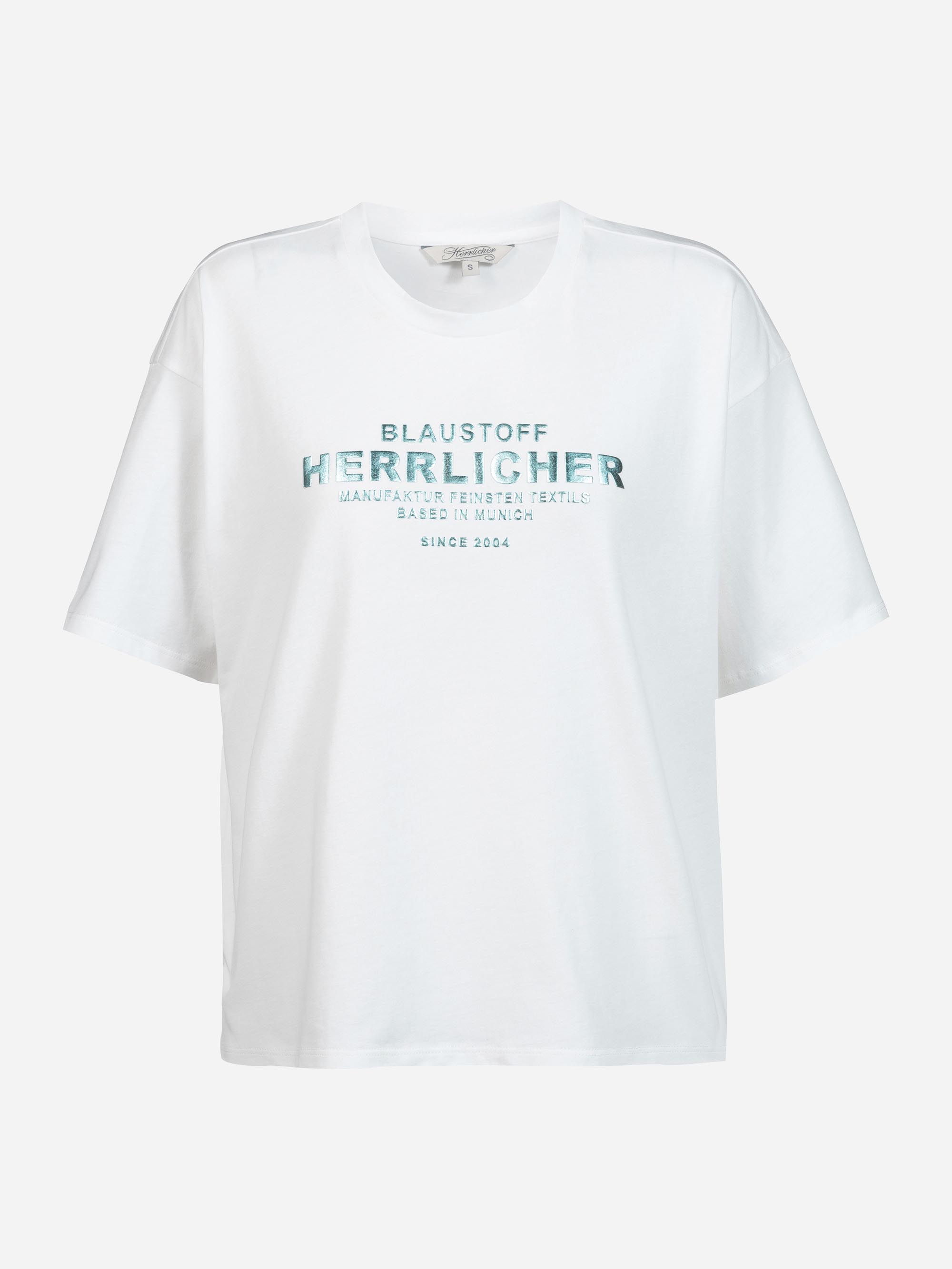 Weißes Kurzarm-T-Shirt mit grauer und blauer Aufschrift auf der Brust: "BLAUSTOFF HERRLICHER MANUFAKTUR FEINSTER TEXTIL BASED IN MUNICH SINCE 2004". Das Shirt hat eine lockere Passform und einen Rundhalsausschnitt.