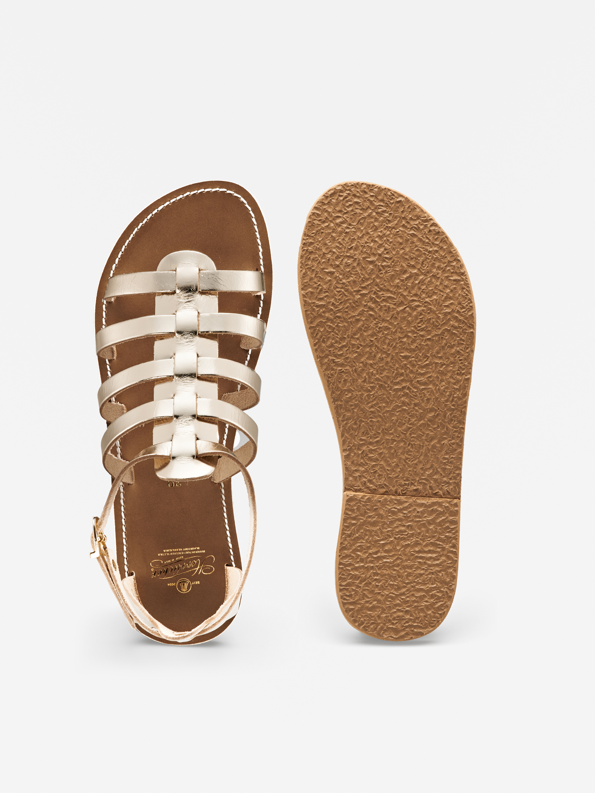 Ein Paar goldfarbene Riemchensandalen mit brauner Sohle, von oben und unten auf weißem Hintergrund abgebildet. Die Sandale hat mehrere metallische Riemen und eine geschlossene Rückseite mit einer kleinen Schnalle.