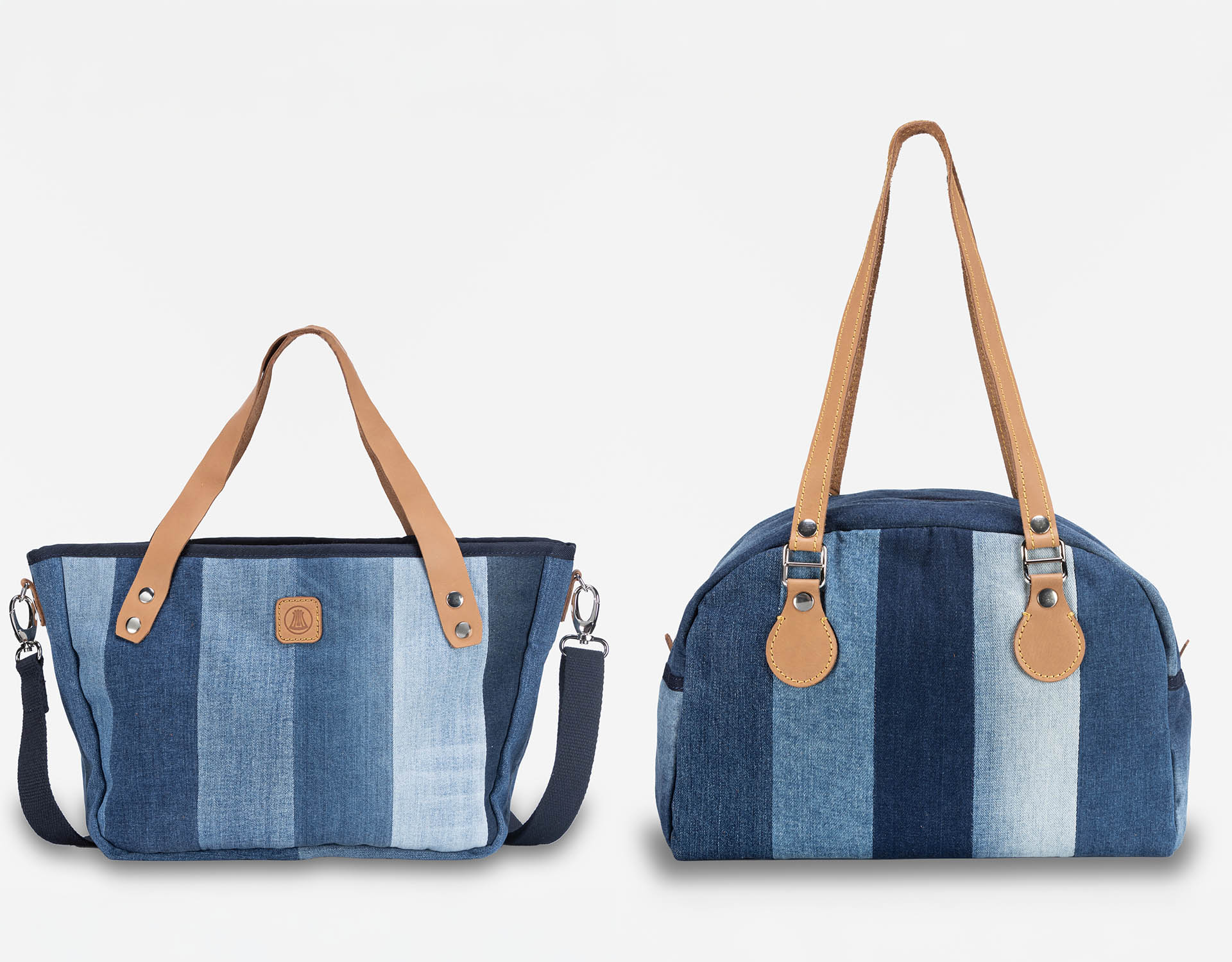 Zwei Handtaschen aus Denim-Stoff mit vertikalen blauen Streifen. Jede Tasche hat hellbraune Ledergriffe und abnehmbare Riemen. Die linke Tasche ist breiter und kürzer, die rechte Tasche ist höher und runder. Beide sind vor einem weißen Hintergrund abge