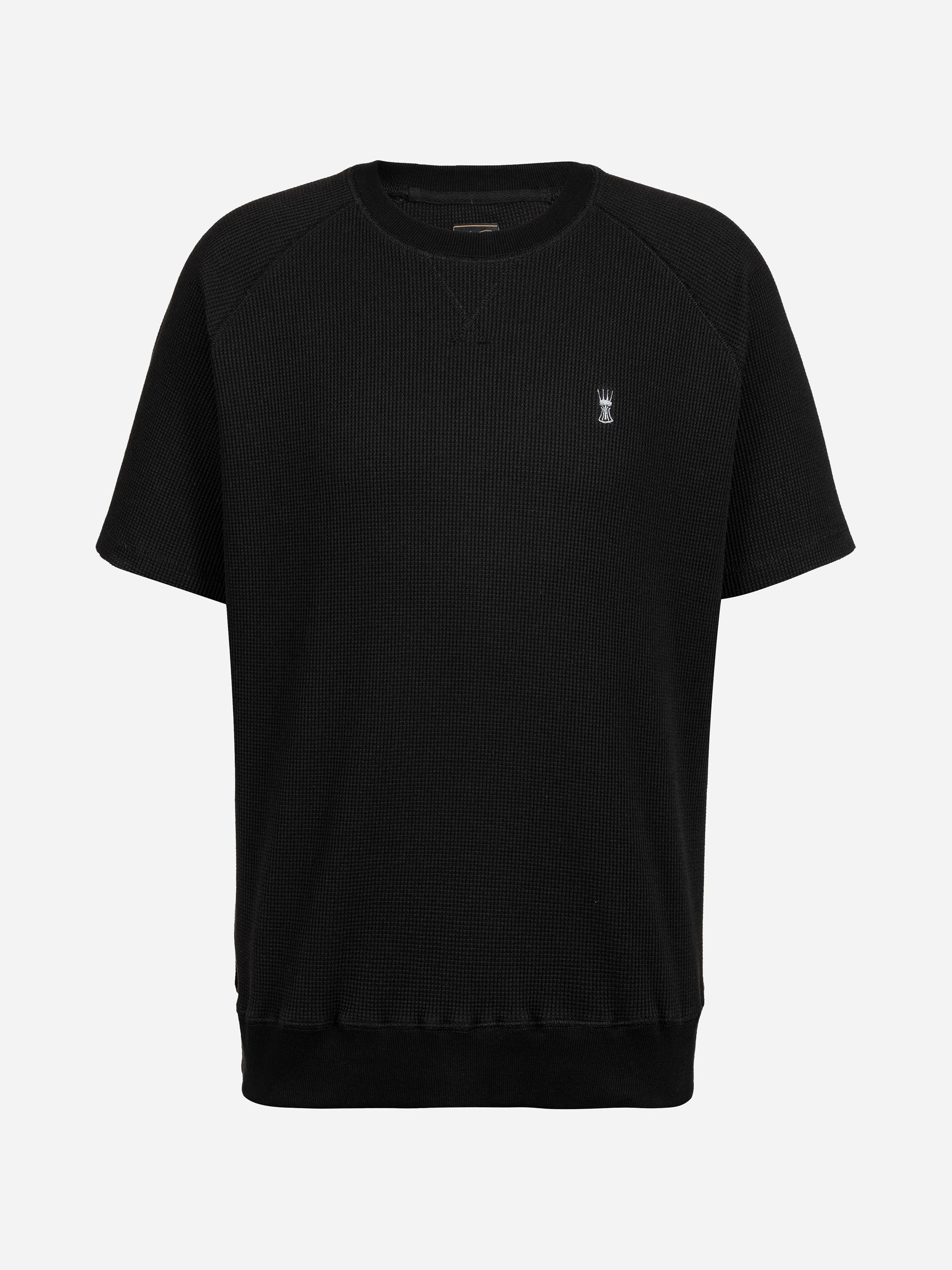 Schwarzes Kurzarm-Shirt mit Rundhalsausschnitt, gerippter Struktur und einem kleinen weißen, gestickten Logo auf der linken Brust auf weißem Grund.