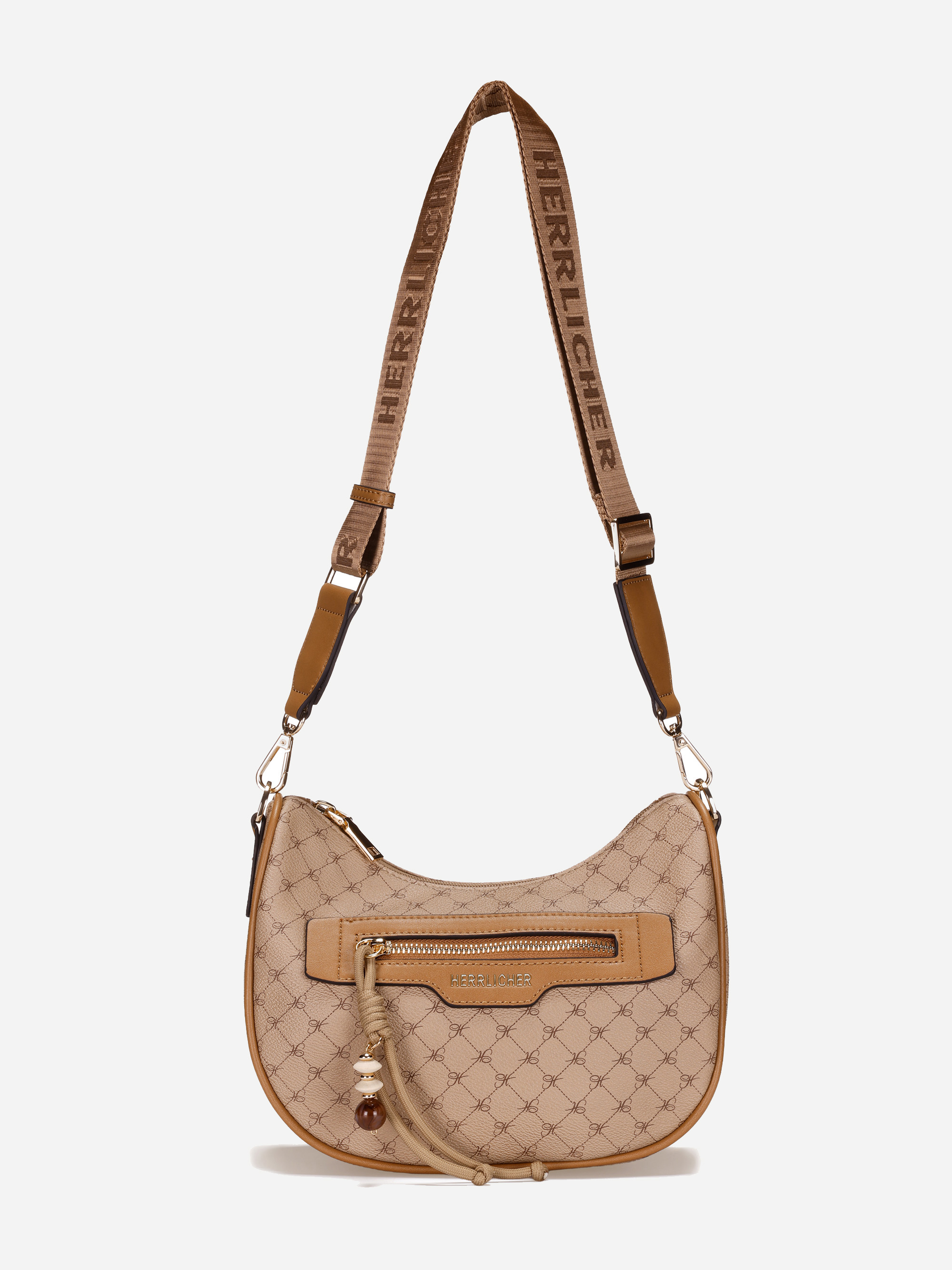 Beigefarbene Umhängetasche mit verstellbarem Riemen und dem Markennamen HERRLICHER. Die Tasche hat ein gemustertes Design, ein vorderes Reißverschlussfach und eine dekorative Quaste mit einem kleinen runden Anhänger.