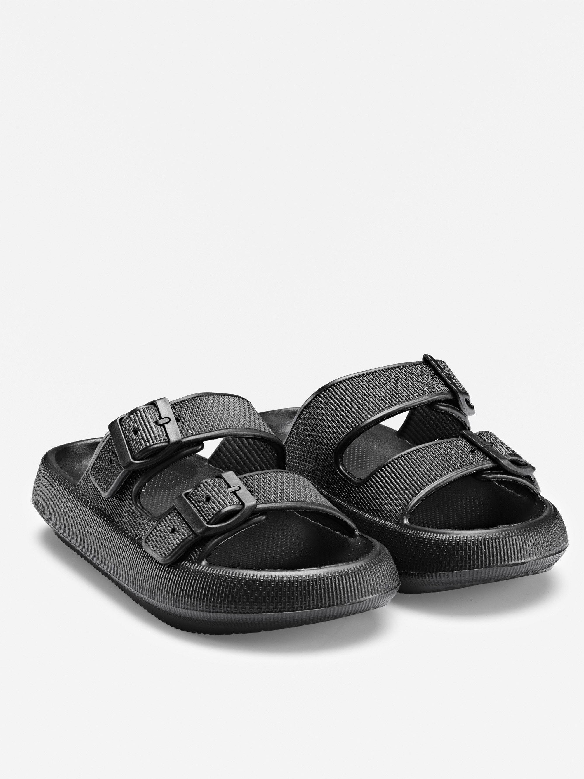 Ein Paar schwarzer Schlupfsandalen mit zwei verstellbaren Schnallenriemen an jedem Schuh, strukturiertem Fußbett und dicken Sohlen, dargestellt auf weißem Hintergrund.