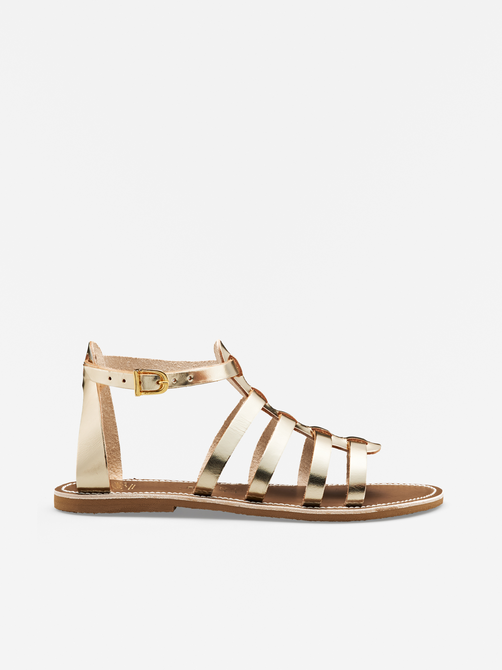 Goldmetallische Riemchensandale mit flacher Sohle, Knöchelriemen und kleinem Schnallendetail auf weißem Hintergrund.
