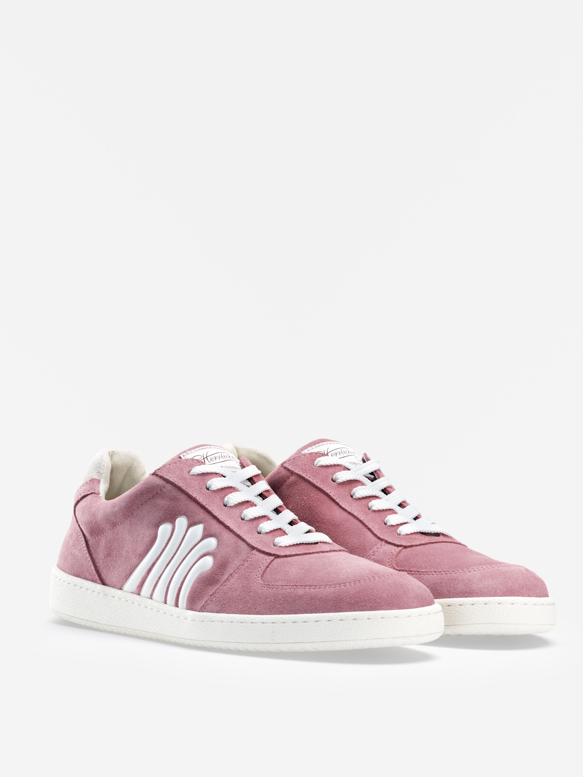 Ein Paar rosa Wildleder-Sneakers mit weißen Schnürsenkeln, weißen Wellenmustern an der Seite und weißen Gummisohlen, die vor einem schlichten weißen Hintergrund stehen.