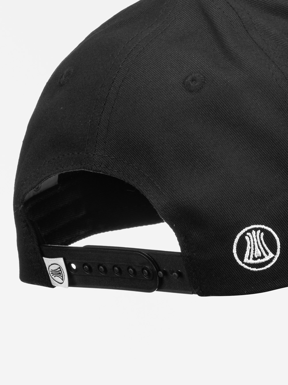 Nahaufnahme der Rückseite einer schwarzen Baseballmütze mit einem schwarzen verstellbaren Riemen mit Metallverschluss und zwei aufgestickten weißen runden Logos.