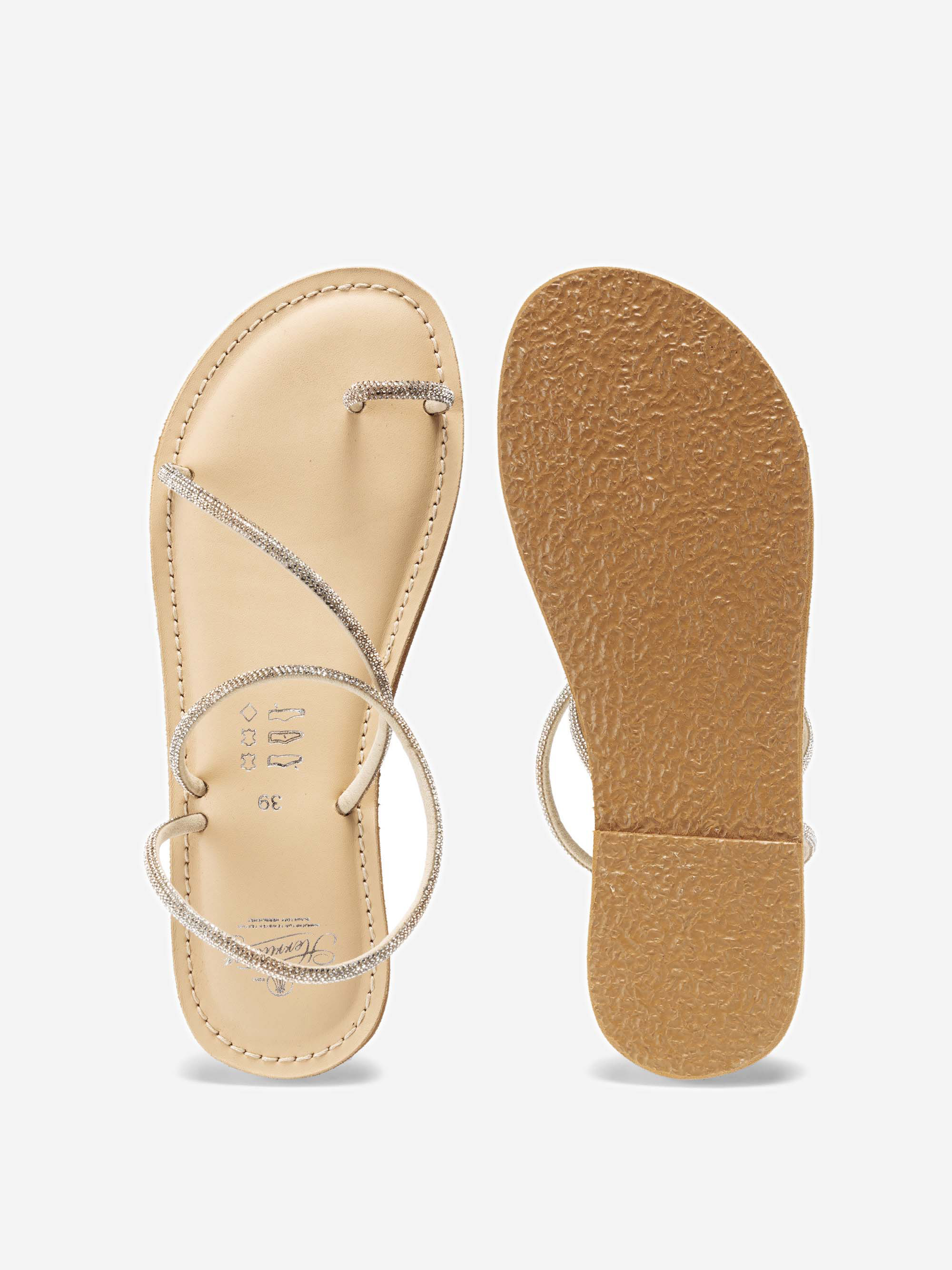 Ein Paar minimalistische beigefarbene flache Sandalen mit dünnen, glitzernden Riemen. Die eine Sandale ist in der Draufsicht mit Fußbett und Riemen abgebildet, die andere zeigt die strukturierte Sohle.
