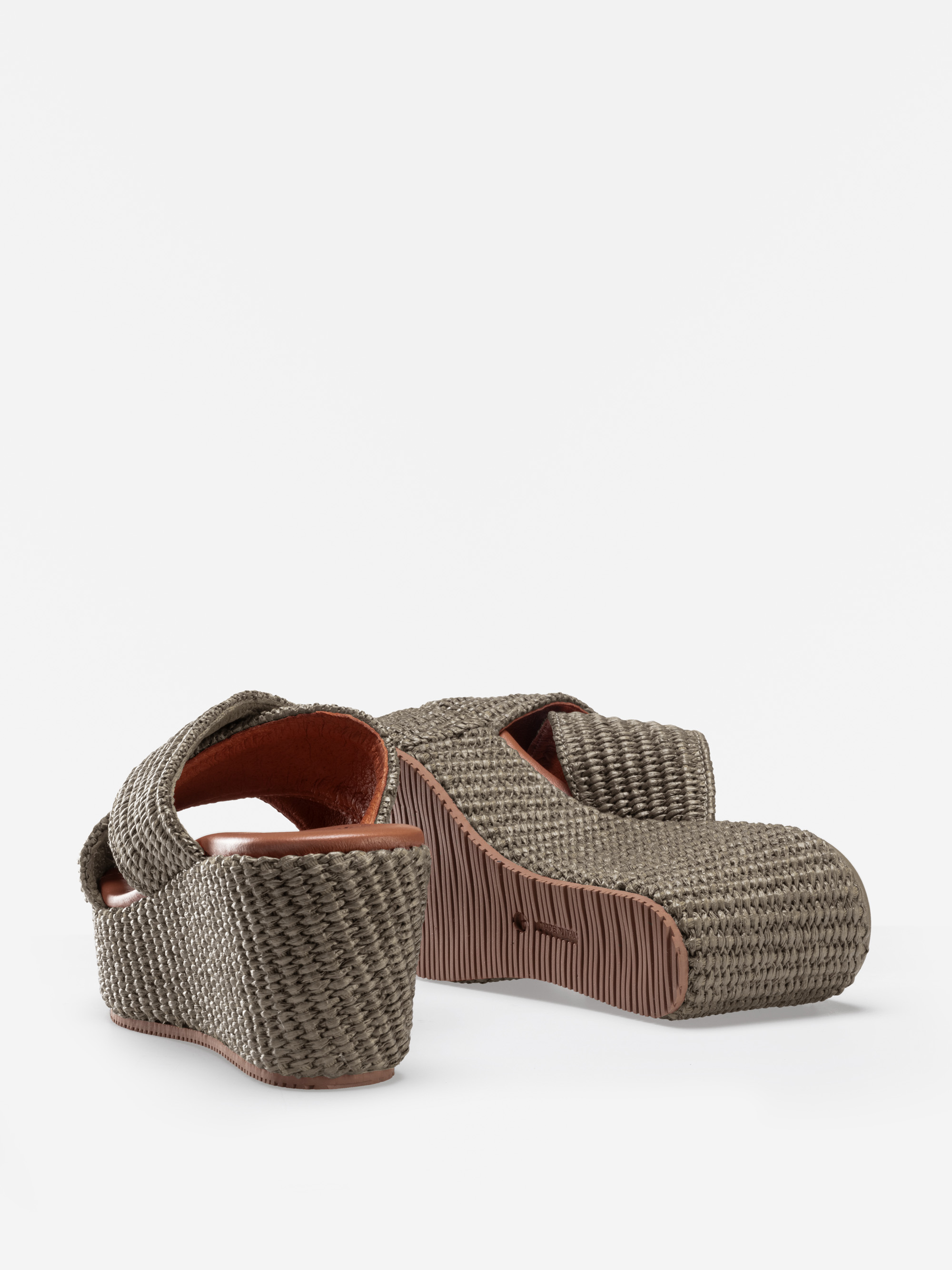 Ein Paar gewebte Plateausandalen in Taupe mit dicken, überkreuzten Riemen und klobigen Sohlen, die vor einem schlichten weißen Hintergrund gezeigt werden.