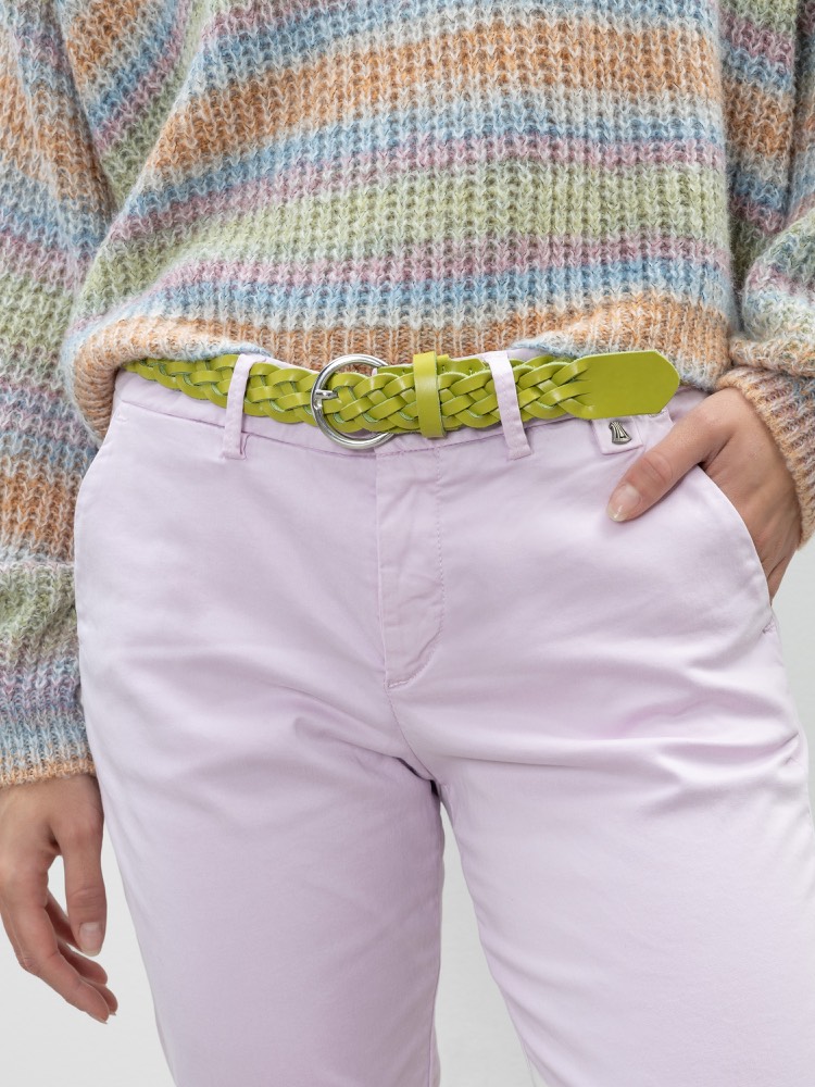 Eine Person trägt eine hellviolette Hose, einen pastellfarbenen Strickpullover und einen hellgrünen gewebten Gürtel mit einer silbernen Schnalle. Eine Hand steckt in der Tasche, und das Bild ist an der Taille abgeschnitten.