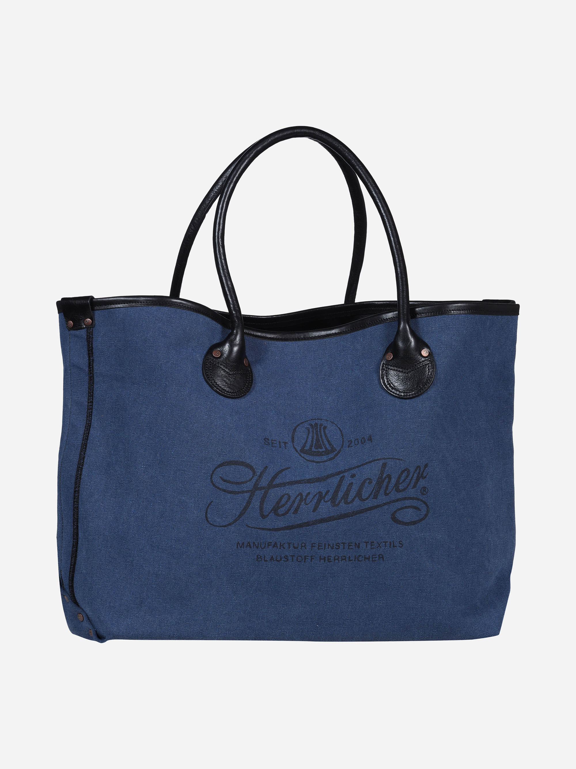 Eine blaue Stofftasche mit schwarzen Ledergriffen und -besätzen. Auf der Vorderseite sind Herrlicher und dekorativer Text in dunkler Schrift aufgedruckt. Die Tasche hat ein lässiges, stilvolles Design.