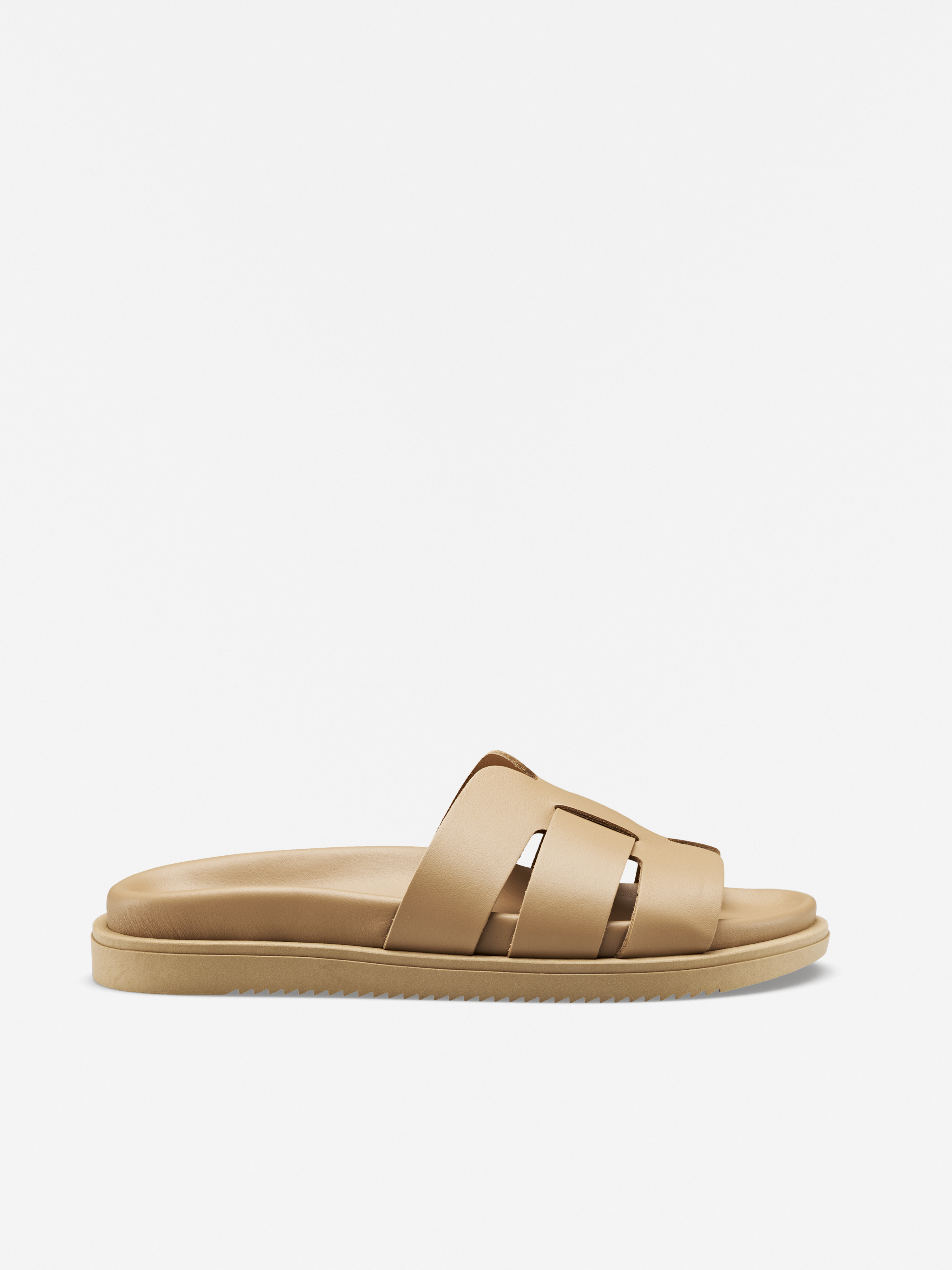 Hellbraune Gleitsandale mit breiten, überkreuzten Riemen und flacher Sohle, in der Seitenansicht auf weißem Hintergrund.