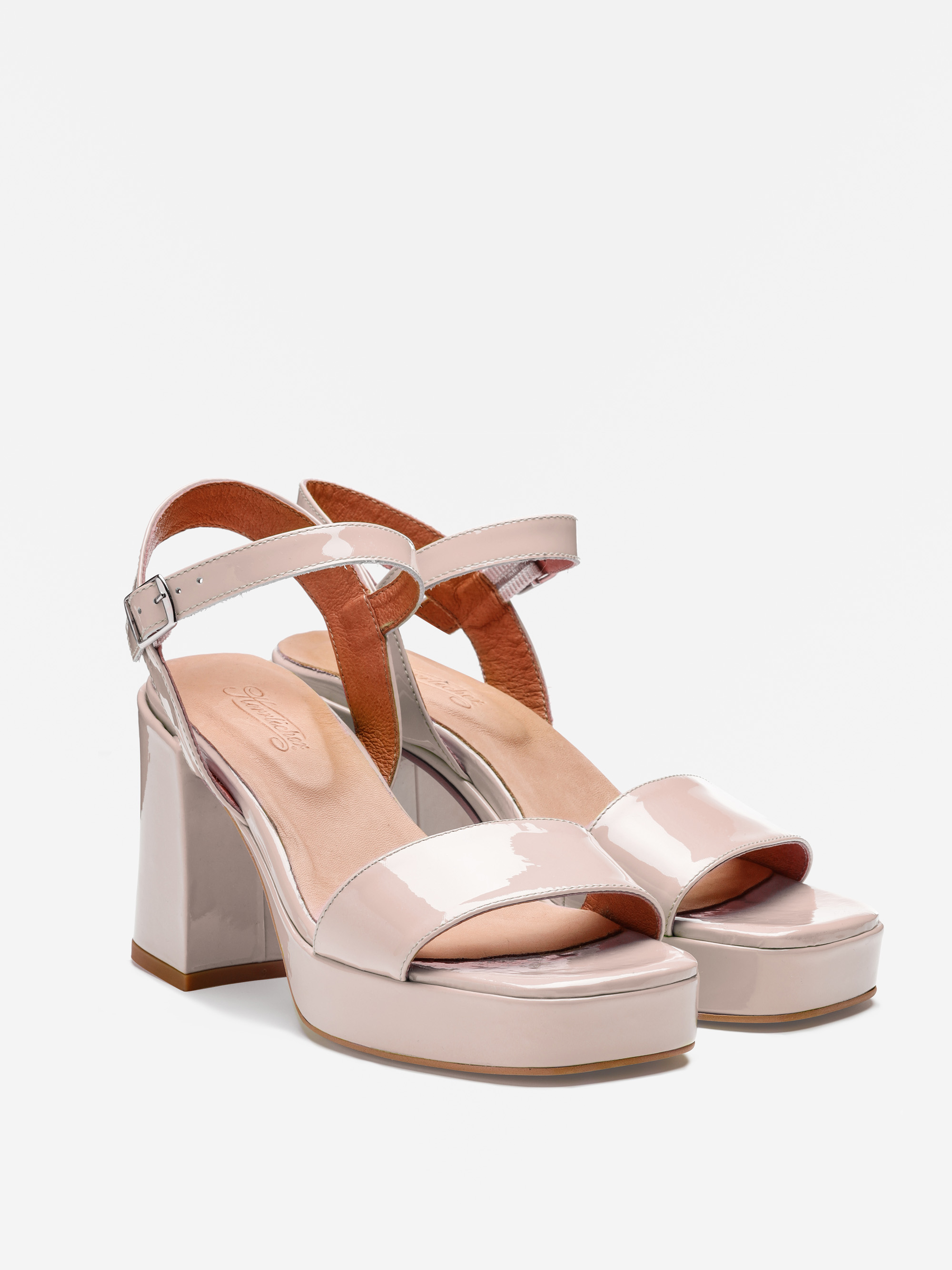 Ein Paar blassrosa Lackleder-Plateau-Sandalen mit klobigen Absätzen, Knöchelriemen und Schnallenverschlüssen, die vor einem weißen Hintergrund gezeigt werden.