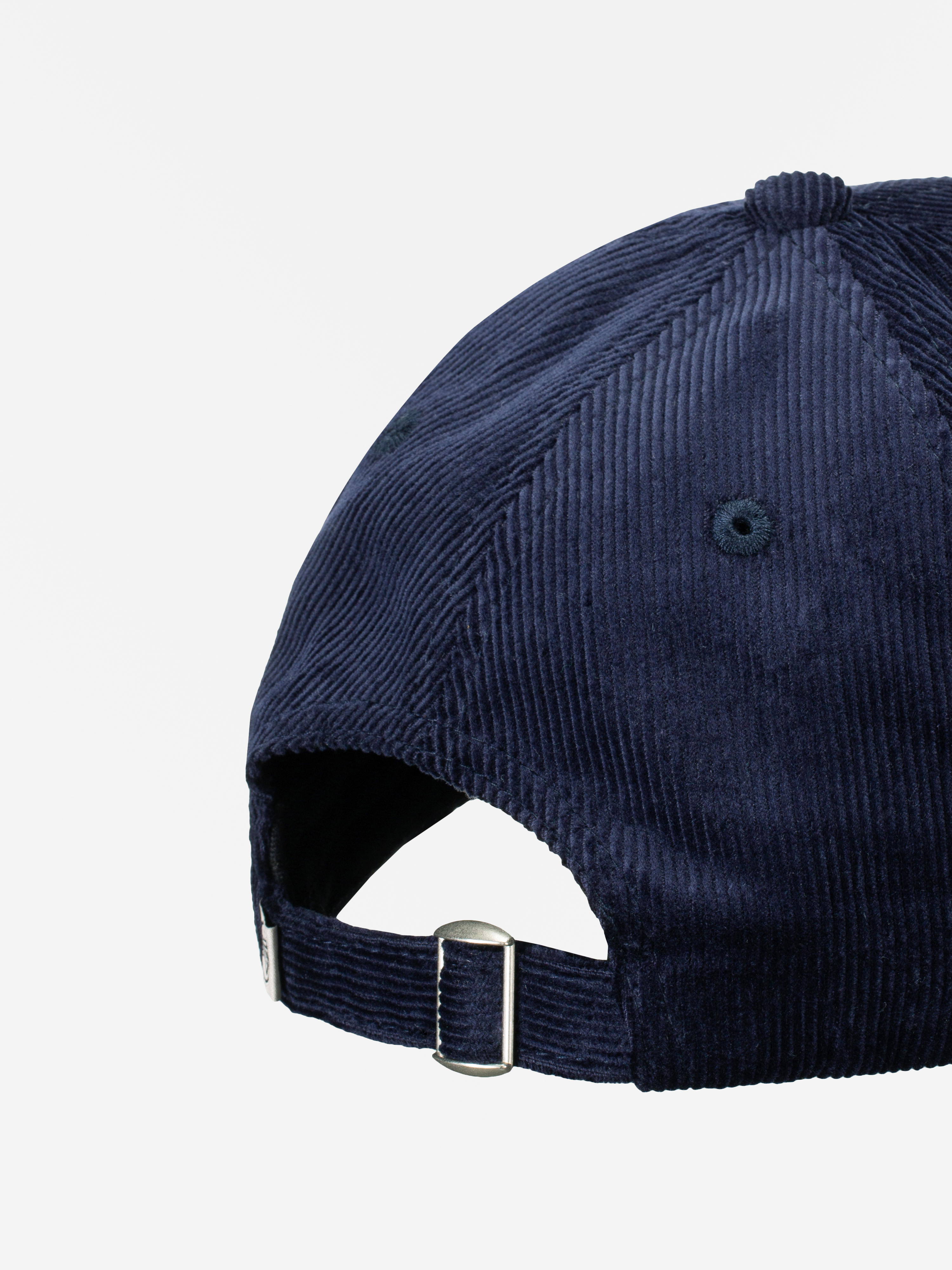 Nahaufnahme der Rückseite einer marineblauen Cord-Baseballmütze mit verstellbarem Stoffband und Metallschnalle vor einem schlichten weißen Hintergrund.