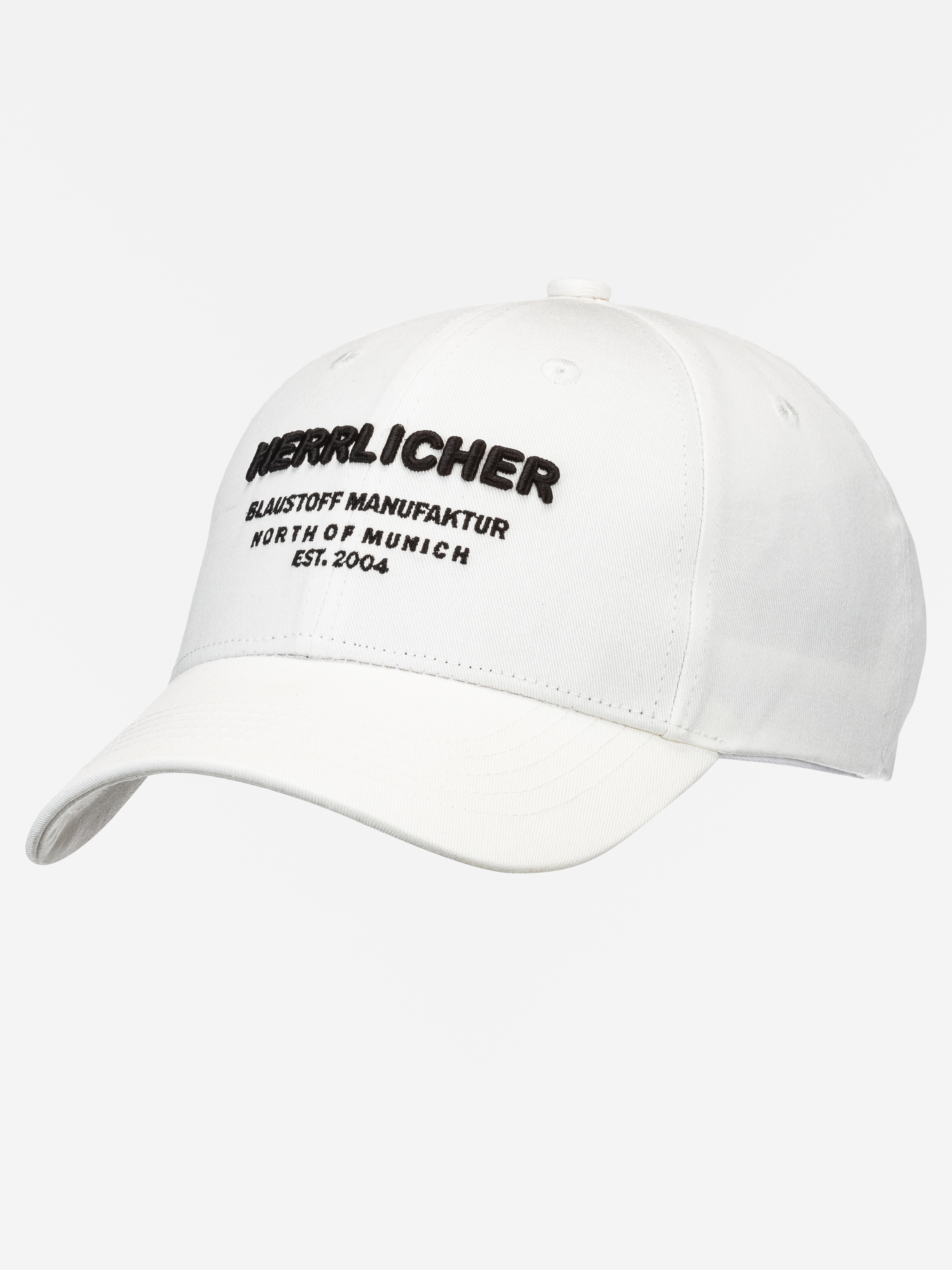 Weiße Baseballkappe mit schwarzer Aufschrift HERRLICHER BLAAUSTOFF MANUFAKTUR NORTH OF MUNICH EST. 2004. Die Kappe ist auf einem schlichten weißen Hintergrund abgebildet.