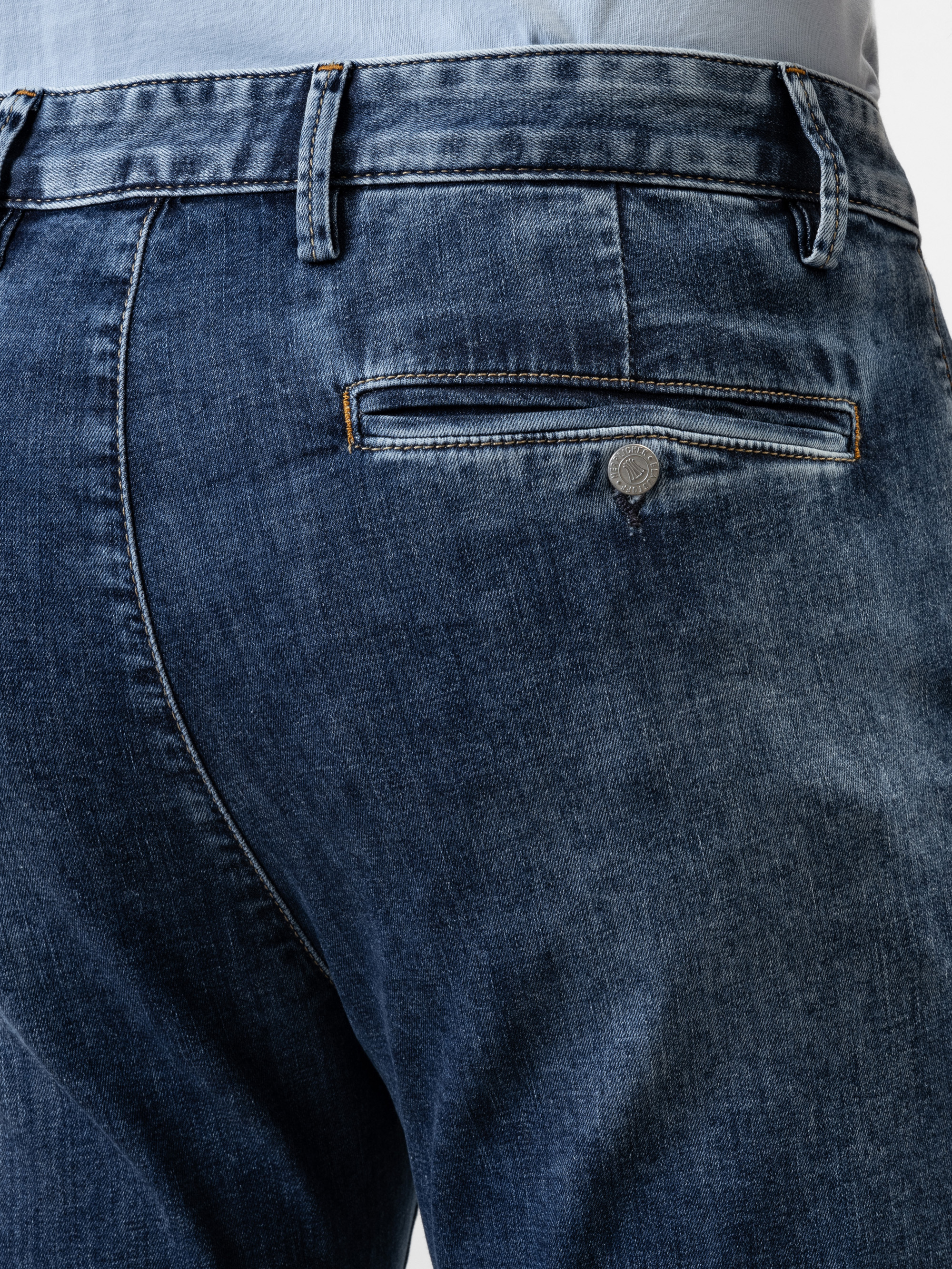 Nahaufnahme des Rückens einer Person, die Blue Denim Jeans trägt, mit einer einzigen Gesäßtasche mit Knopf und Gürtelschlaufen am Bund.