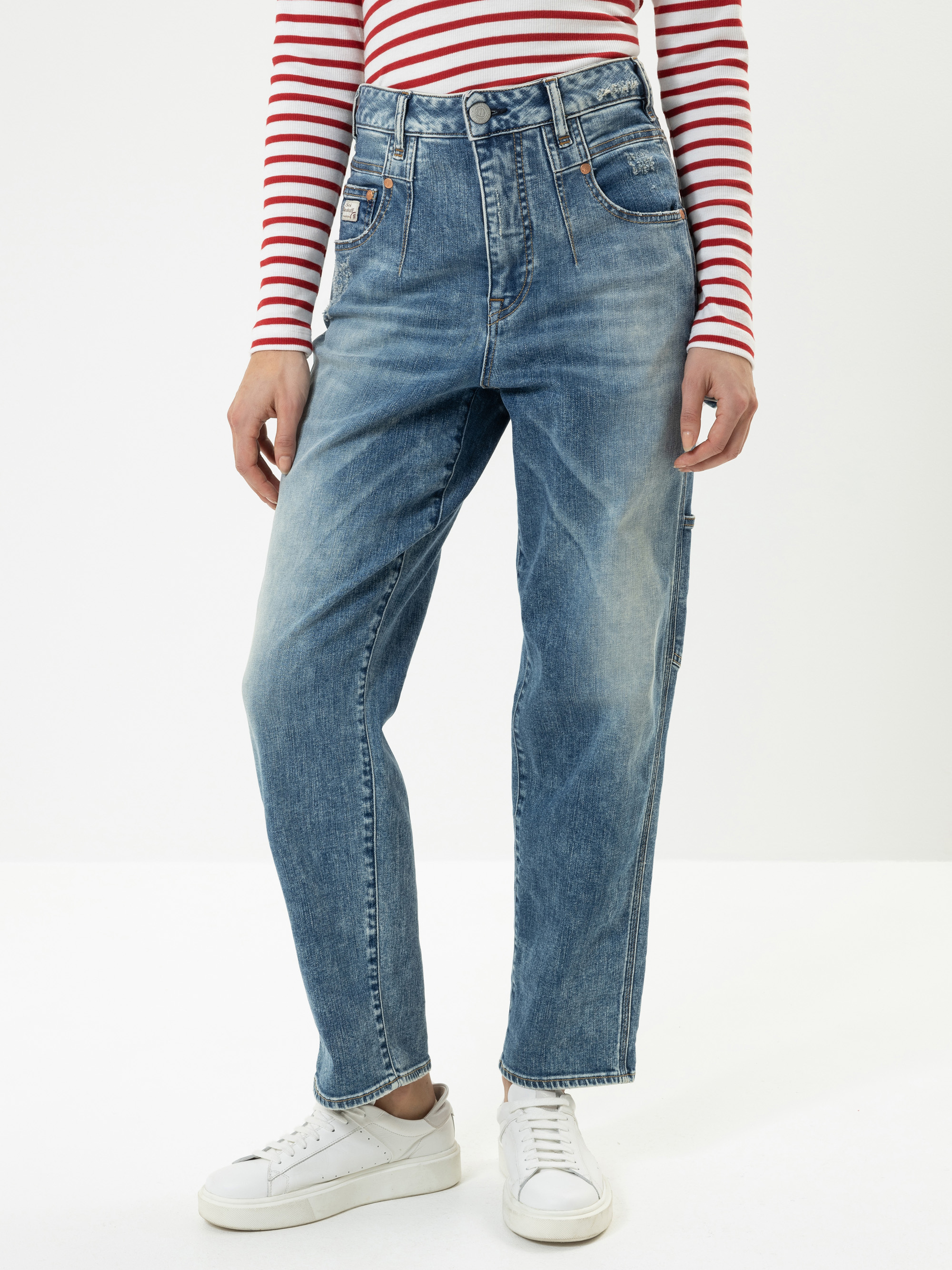 Person in hellblauen Jeans mit hoher Taille, einem rot-weiß gestreiften langärmeligen Hemd und weißen Turnschuhen vor einem schlichten weißen Hintergrund. Nur der Körper von den Schultern abwärts ist sichtbar.