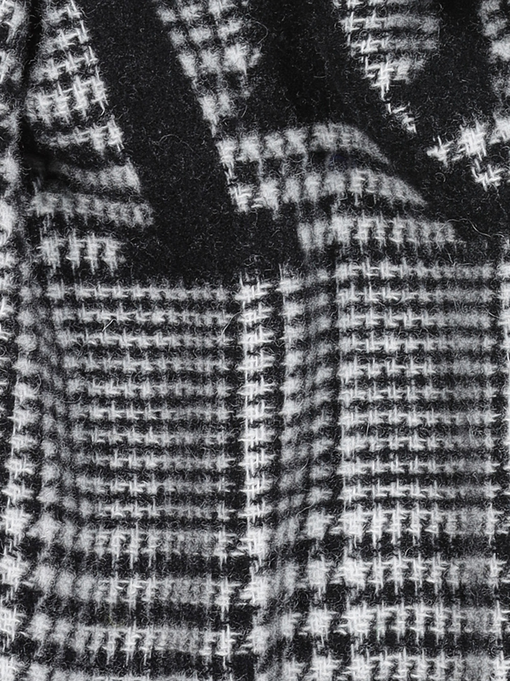 Nahaufnahme eines schwarz-weiß-grauen karierten Stoffmusters, das ein ausgeprägtes Hahnentritt- und Karomuster mit weichen, strukturierten Fasern zeigt.