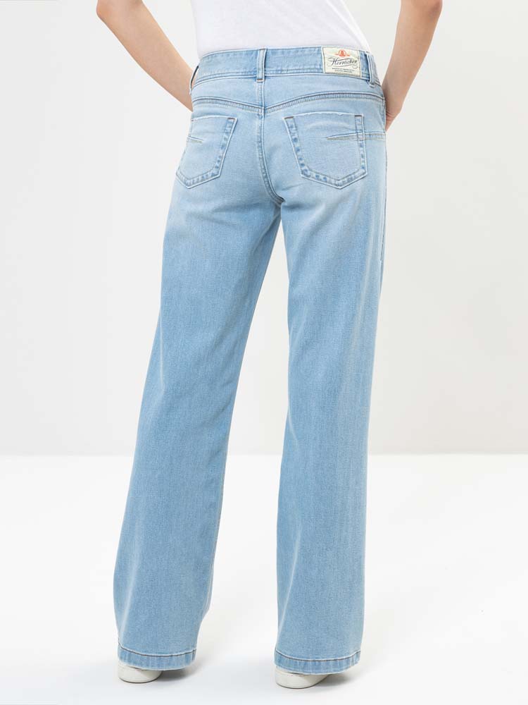 Eine Person, die hellblaue, hochtaillierte Jeans mit weitem Bein und ein weißes Oberteil trägt, von hinten vor einem einfarbig weißen Hintergrund dargestellt.