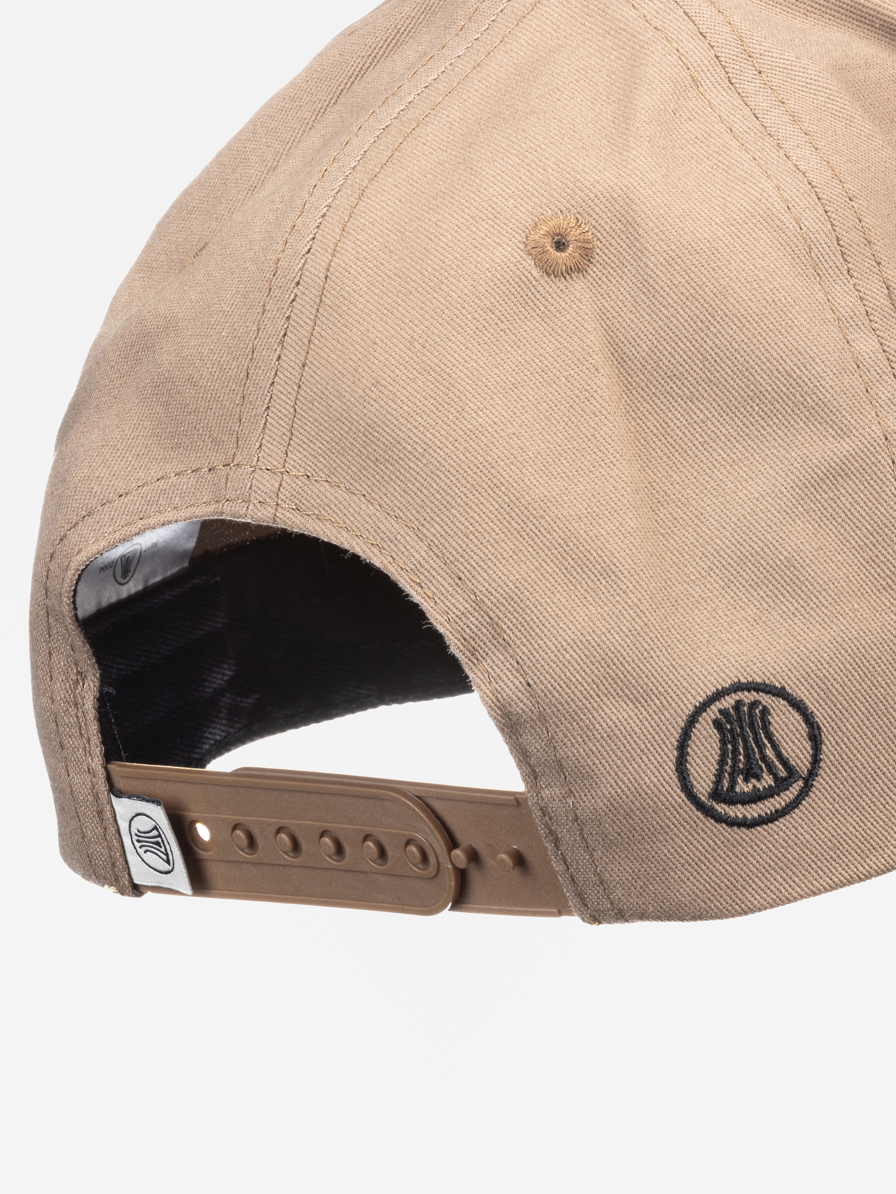 Nahaufnahme der Rückseite einer hellbraunen Baseballmütze mit schwarzen Nähten, aufgesticktem kreisförmigem Logo und verstellbarem braunem Kunststoffband.