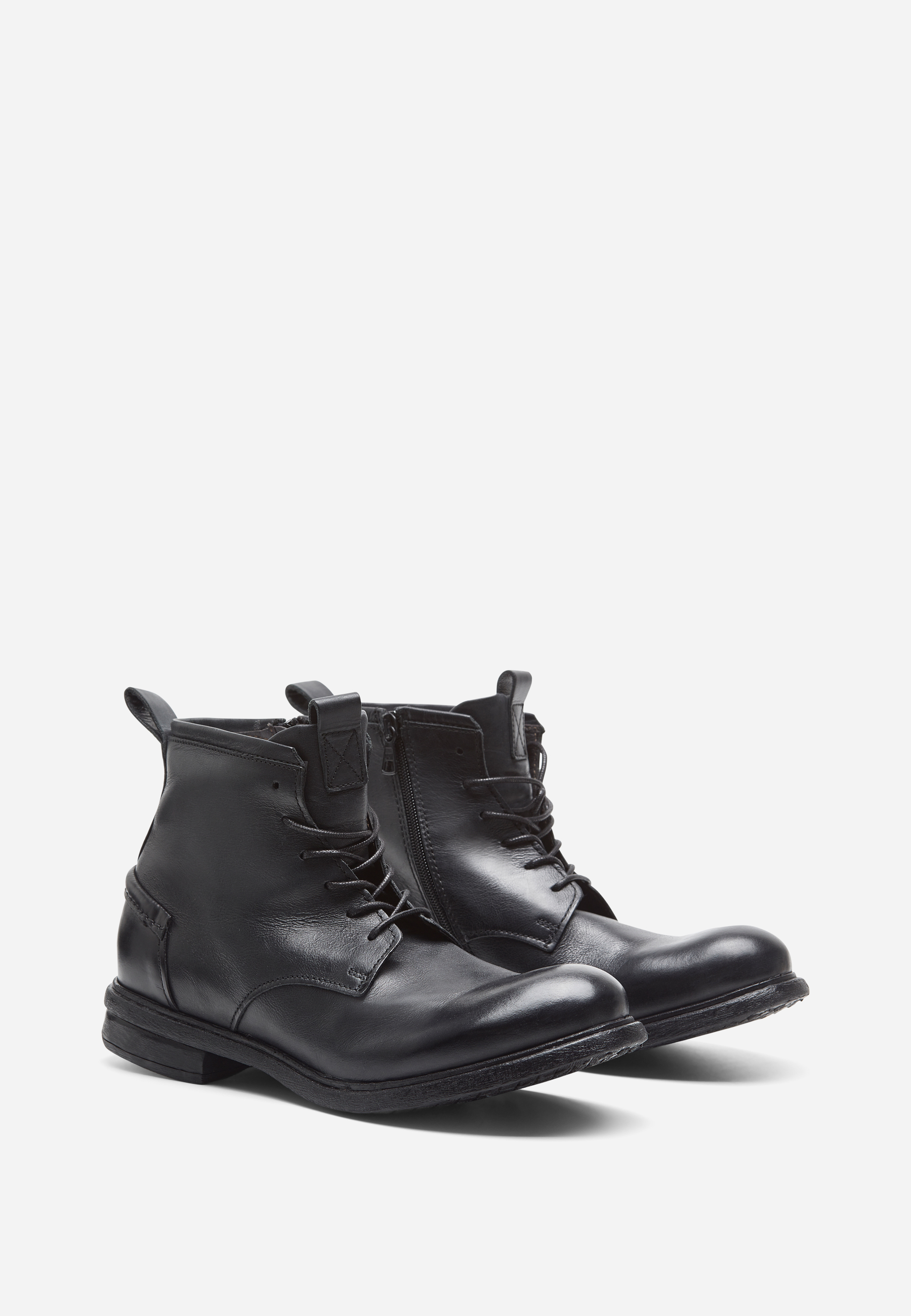 Ein Paar schwarze Lederstiefel zum Schnüren mit seitlichen Reißverschlüssen auf weißem Hintergrund. Die Stiefel haben eine abgerundete Zehe, einen niedrigen Absatz und eine leicht strukturierte Sohle.