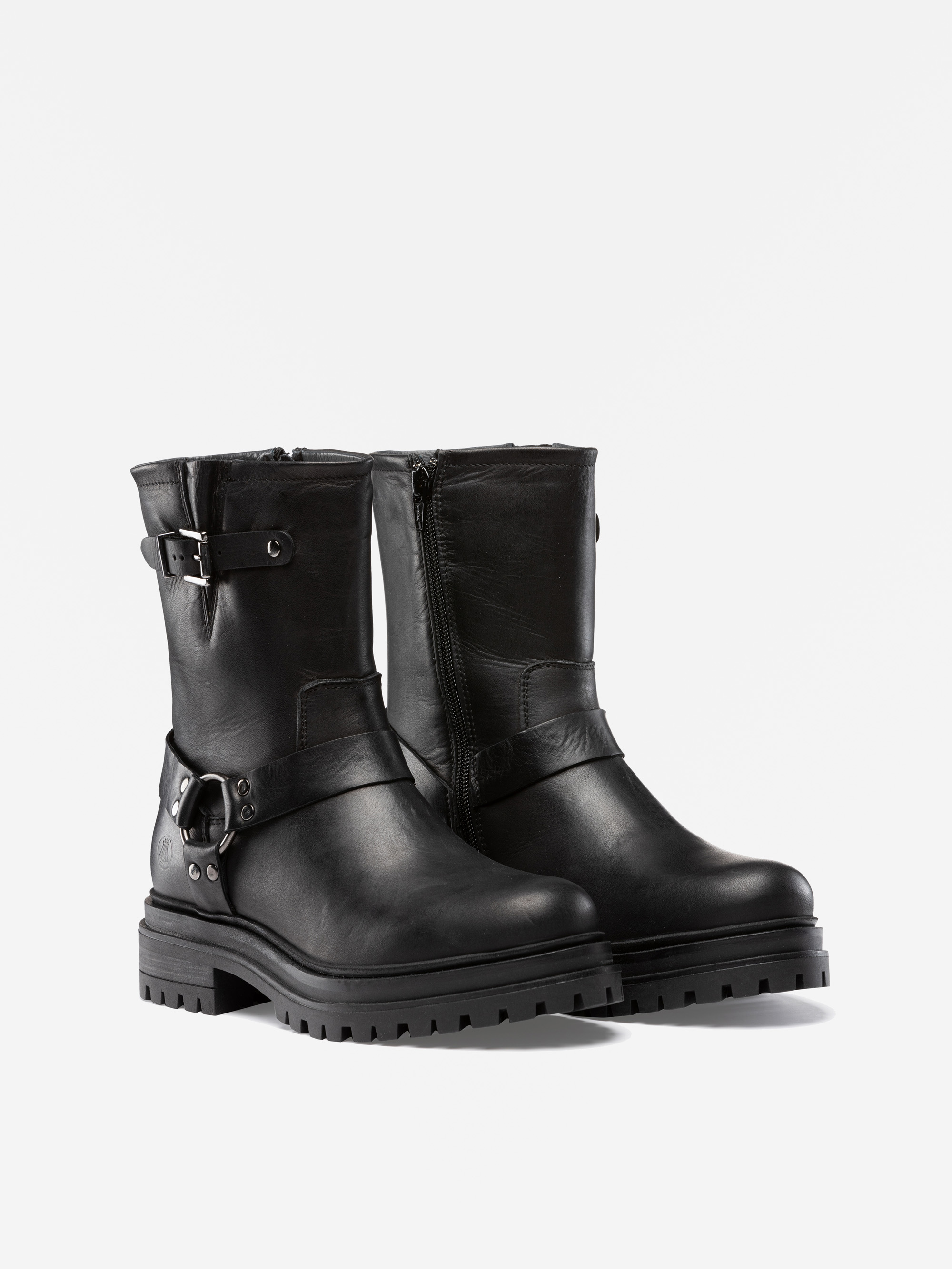 Ein Paar schwarze, halbhohe Lederstiefel mit klobigen Stollensohlen, Schnallenriemen um die Knöchel und seitlichen Reißverschlüssen, die vor einem schlichten weißen Hintergrund stehen.