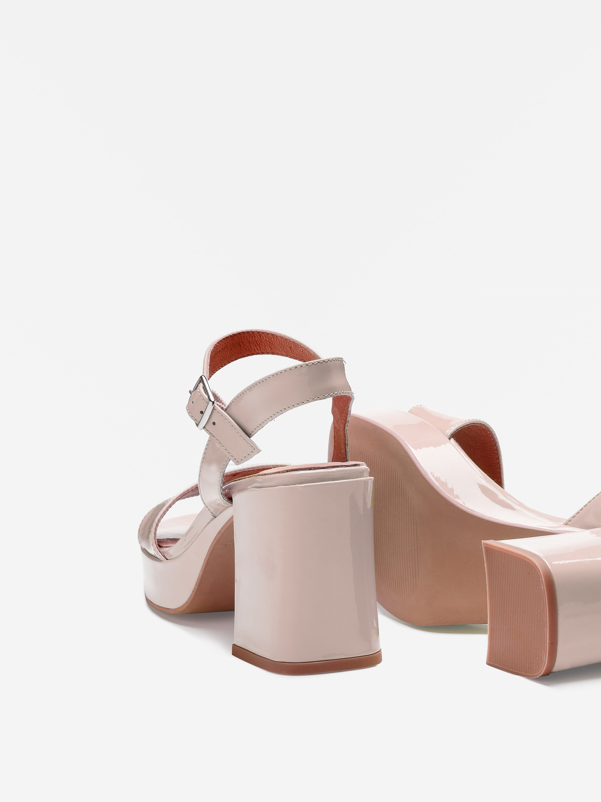 Ein Paar glänzender, hellrosa Plateausandalen mit hohen Absätzen, Knöchelriemen und Schnallenverschlüssen, dargestellt von hinten und von der Seite auf weißem Hintergrund.