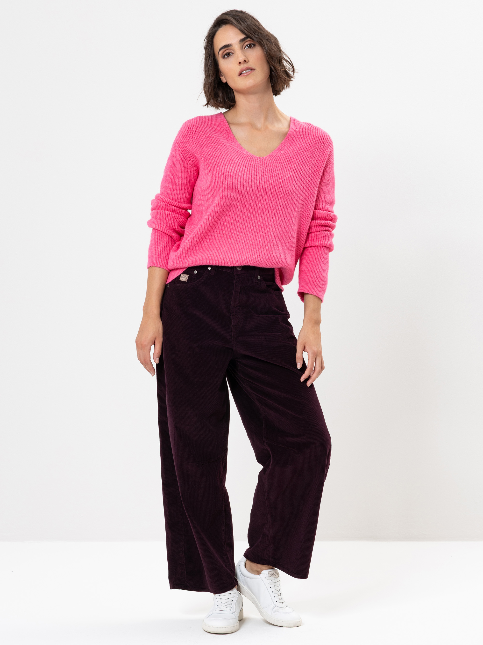 Eine Frau in rosa Pullover und Hose.