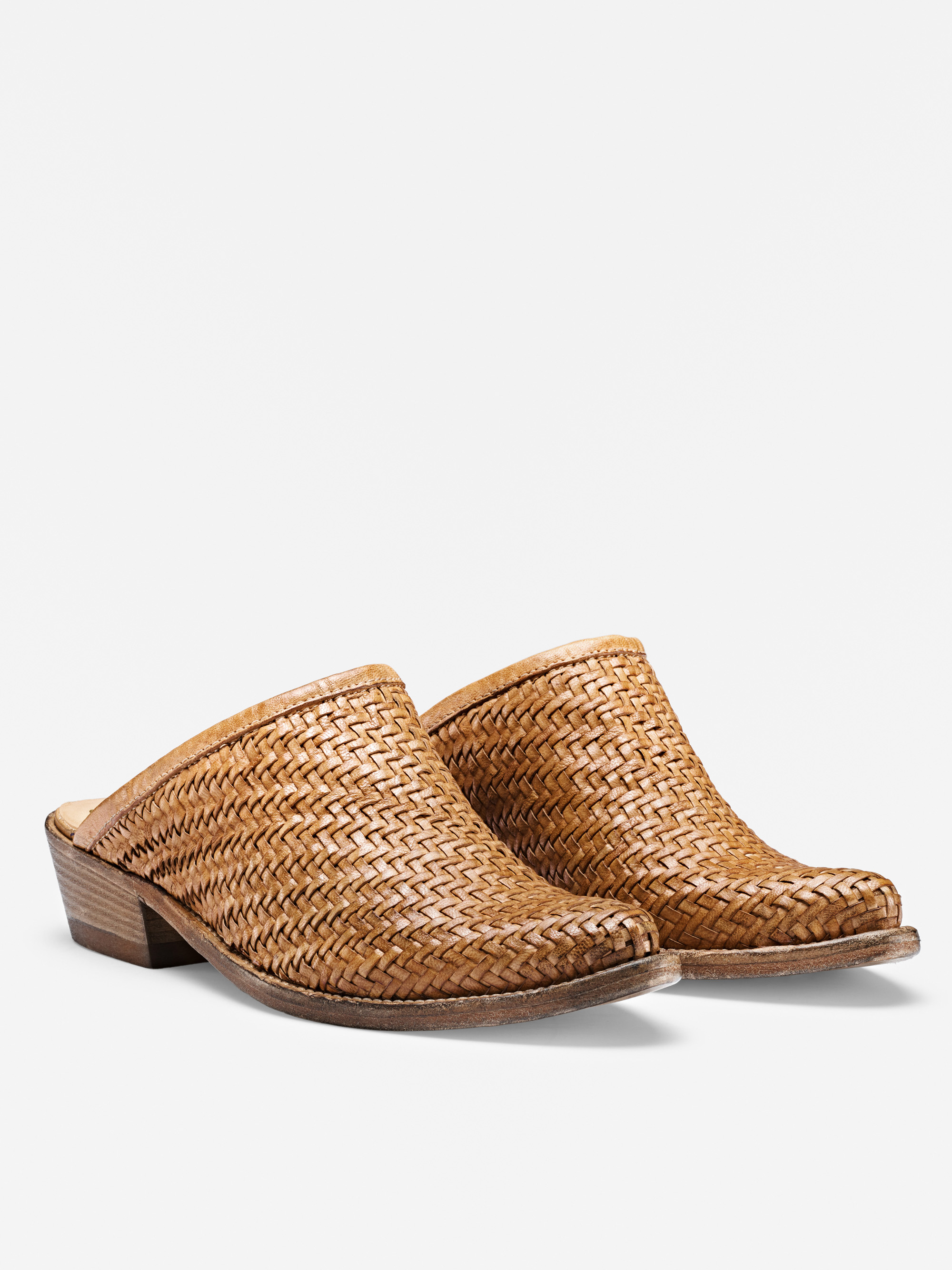 Ein Paar hellbraune, geflochtene Lederslipper mit niedrigem, gestapeltem Absatz und geschlossenen Zehen, dargestellt auf weißem Hintergrund.