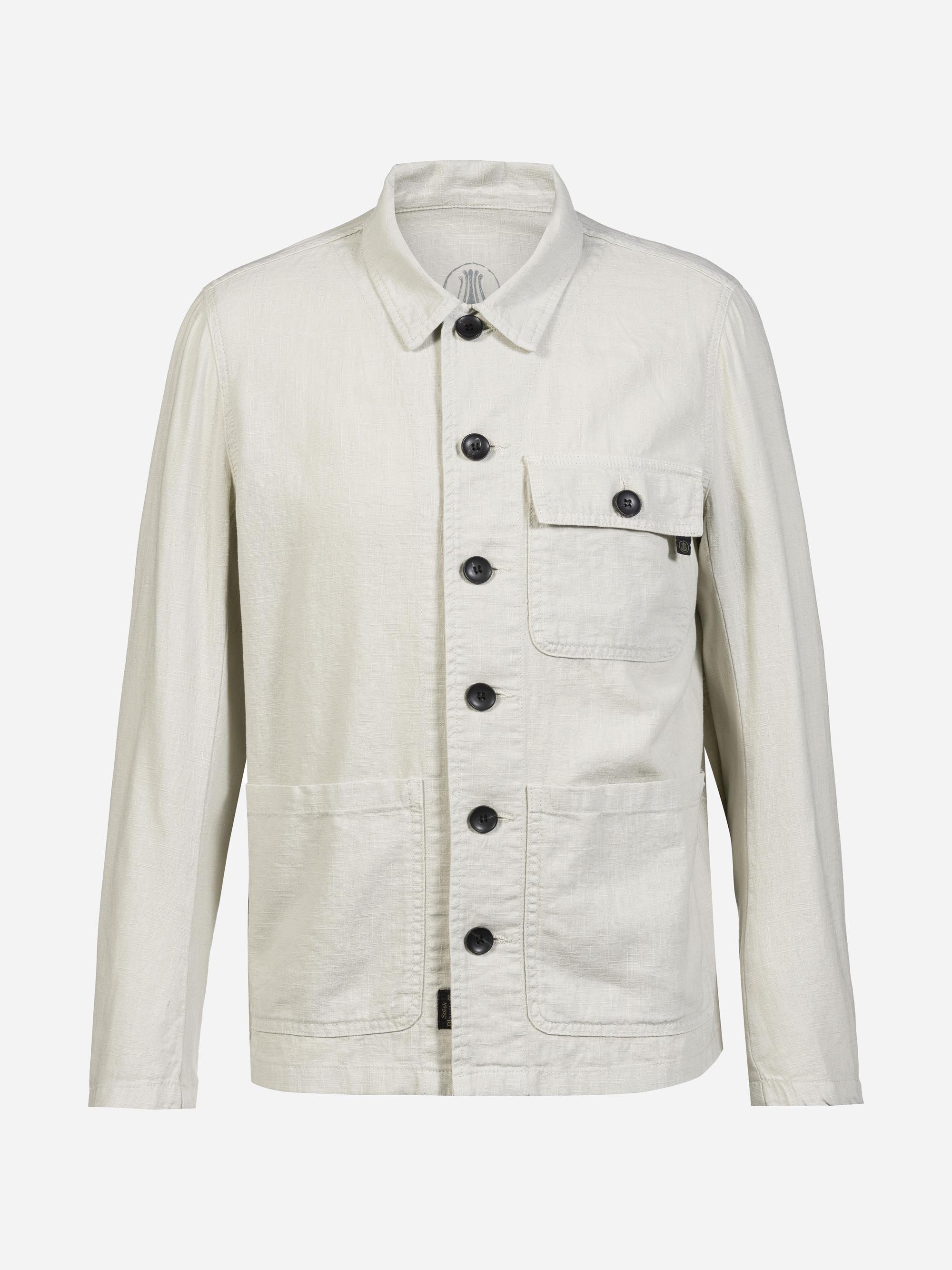 Cremefarbene, langärmelige Jacke mit schwarzen Knöpfen, spitzem Kragen, zwei großen unteren Vordertaschen und einer Brusttasche mit Reißverschluss auf weißem Grund.