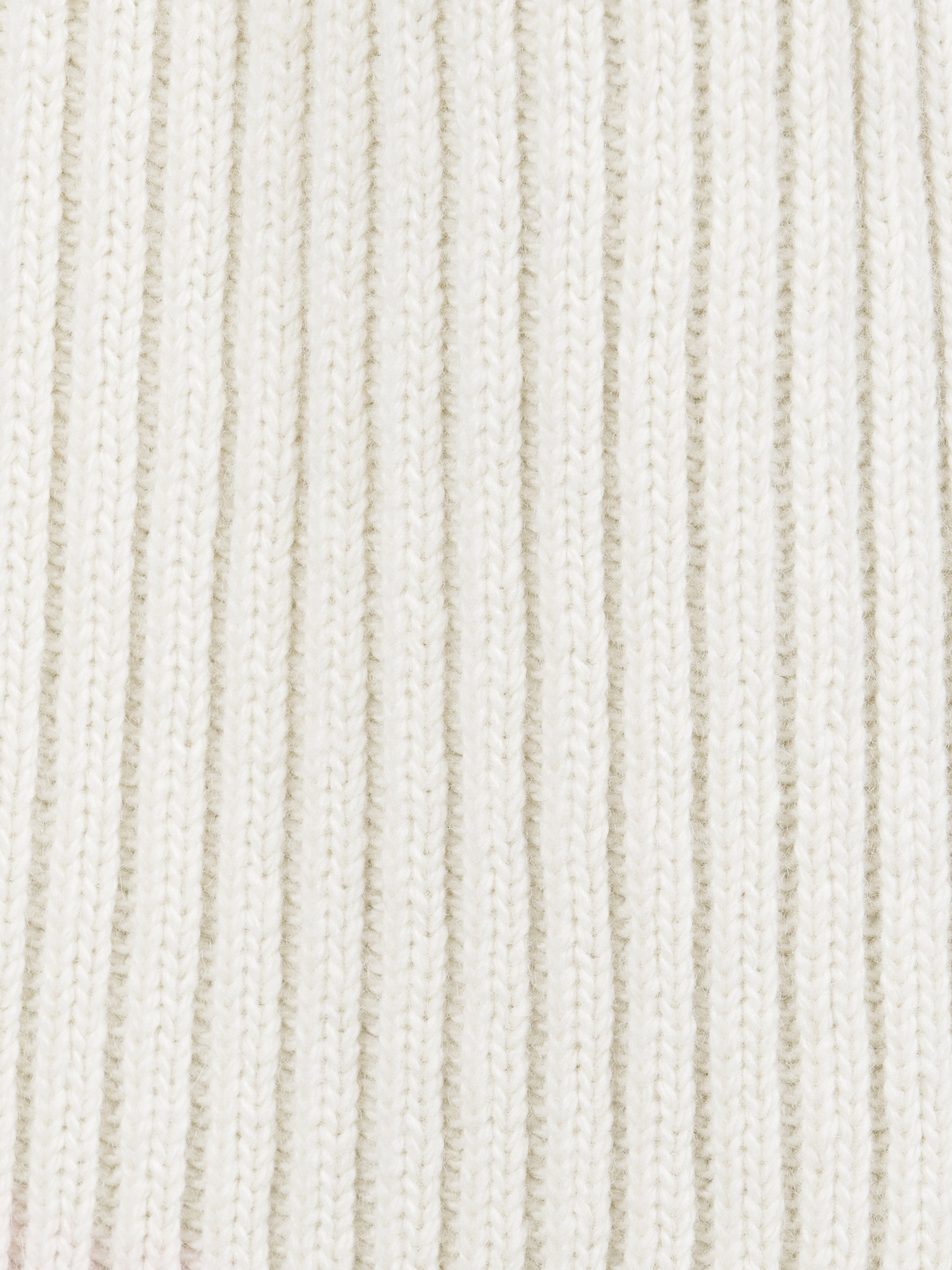 Nahaufnahme eines cremefarbenen, gerippten Strickstoffs mit vertikalen, parallel verlaufenden Strukturlinien, die ein weiches, kuscheliges und warmes Aussehen erzeugen.
