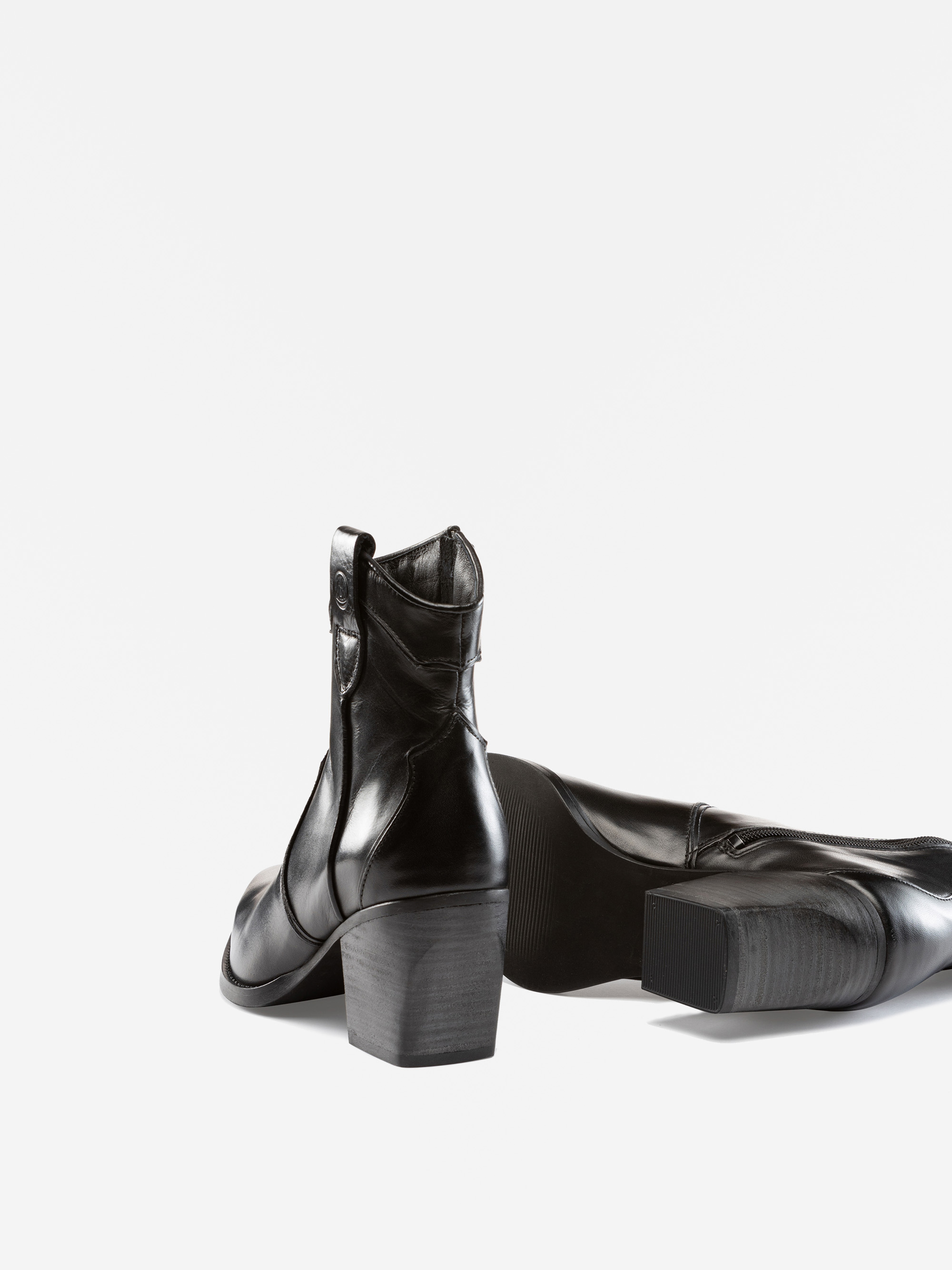 Zwei schwarze Lederstiefel mit Blockabsätzen sind vor einem weißen Hintergrund abgebildet. Ein Stiefel steht aufrecht, während der andere auf der Seite liegt und die Sohle und den seitlichen Reißverschluss zeigt.