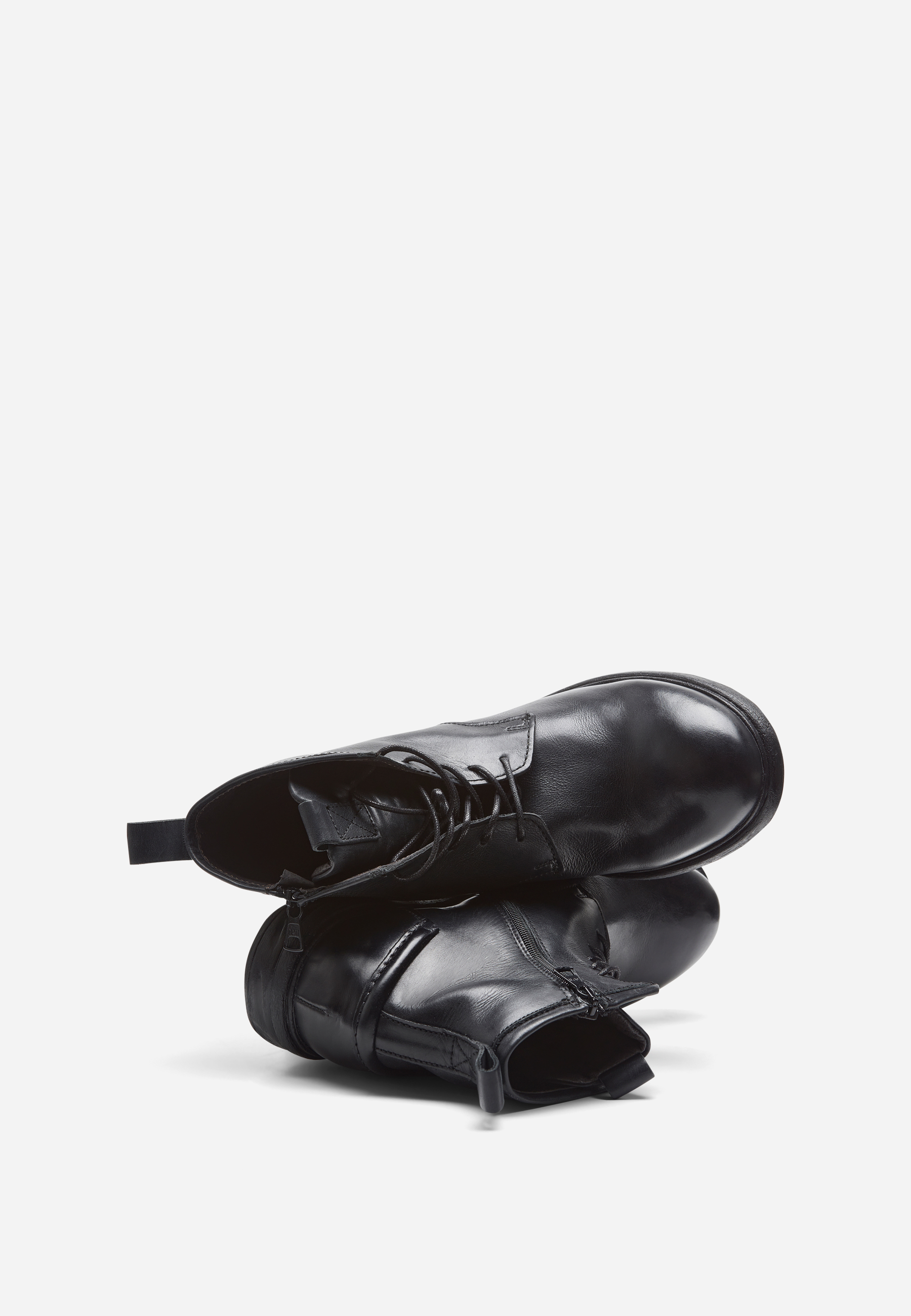 Ein Paar schwarze Lederschnürstiefel, die vor einem schlichten weißen Hintergrund übereinander gestapelt sind.
