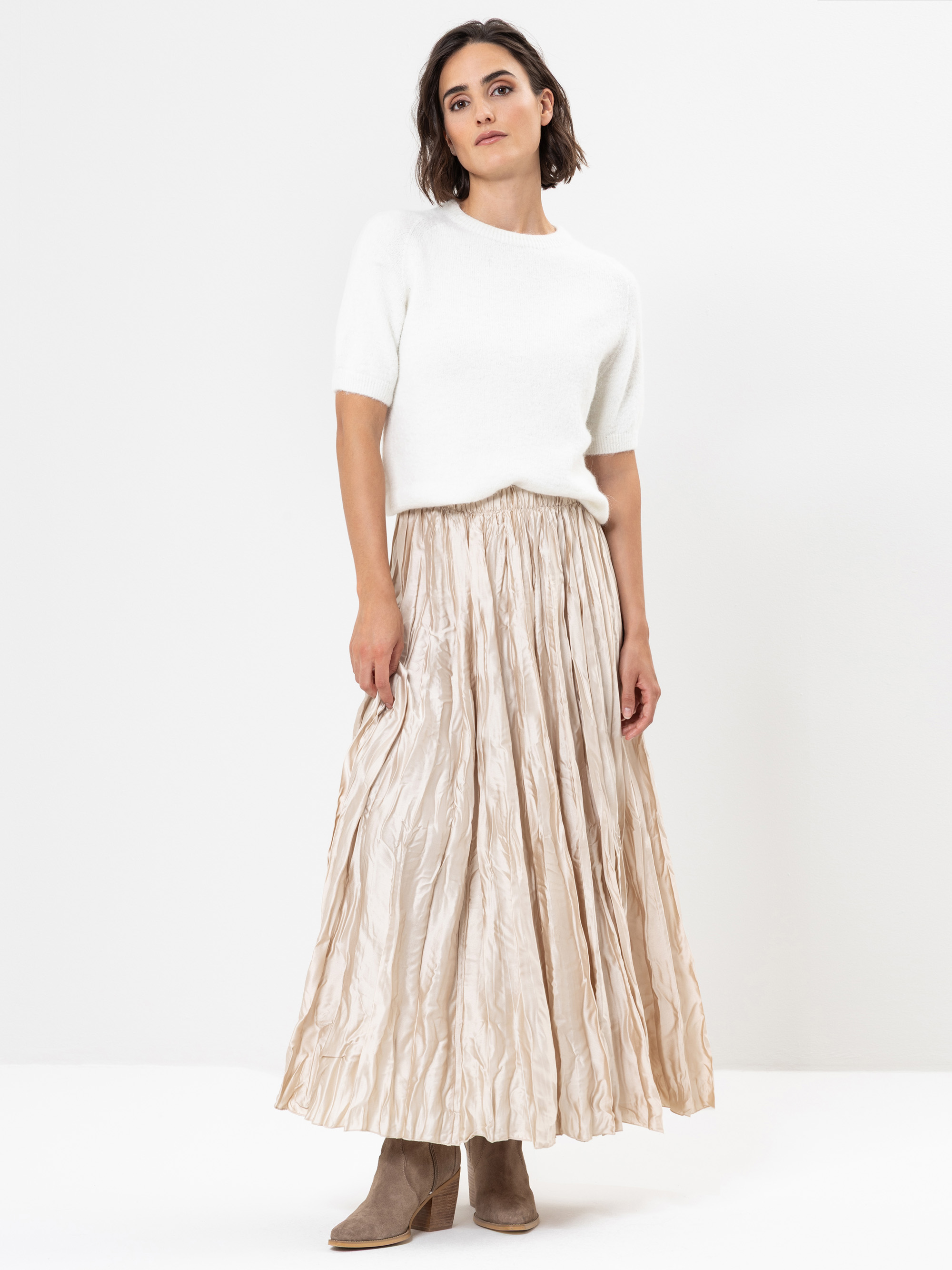 Eine Frau in einem weißen Pullover und einem langen Rock.