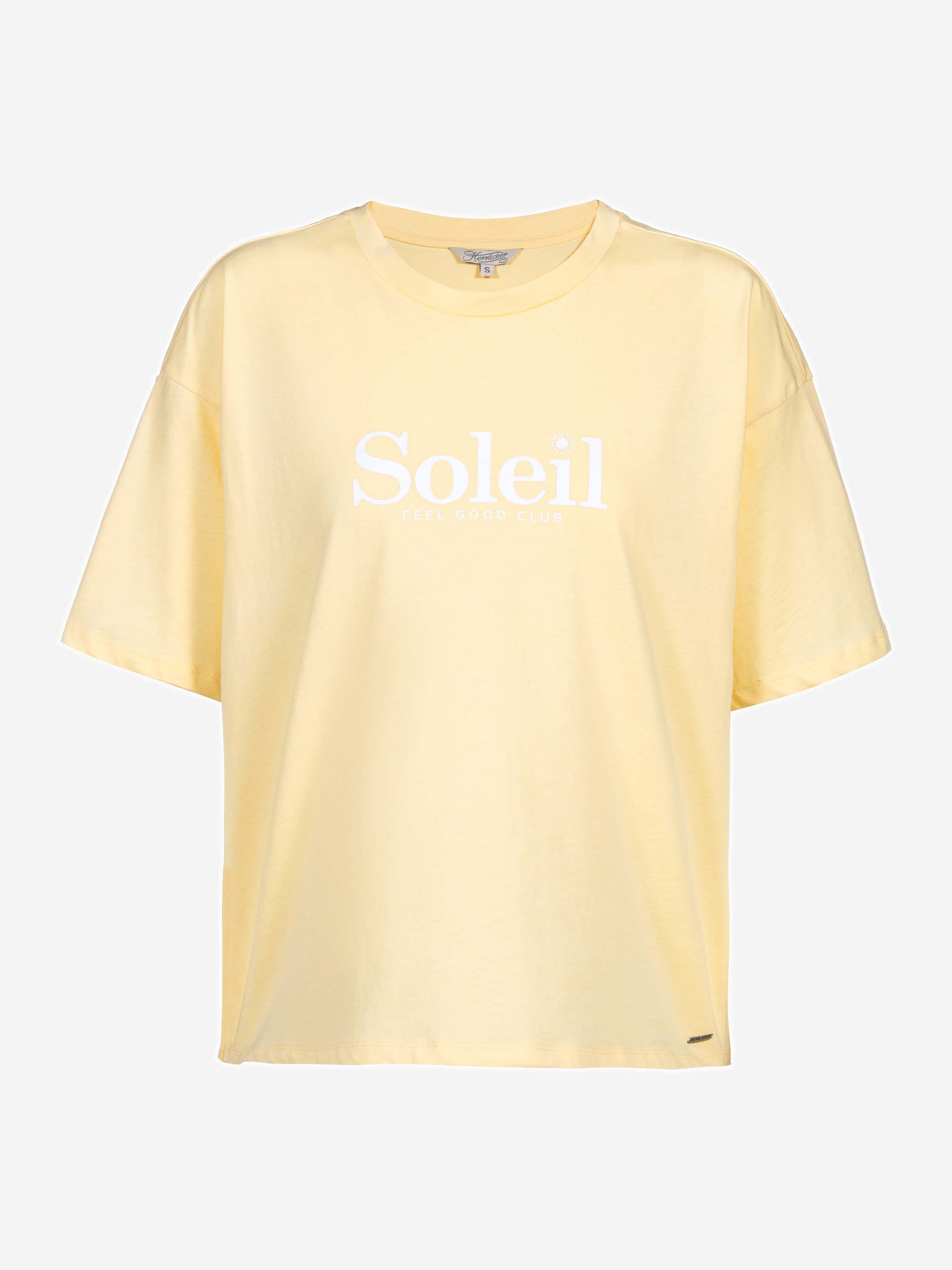Hellgelbes Oversize-T-Shirt mit kurzen Ärmeln. Auf der Vorderseite des T-Shirts sind das Wort Soleil und der Schriftzug FEEL GOOD CLUB in weiß aufgedruckt. Der Hintergrund ist einfarbig weiß.