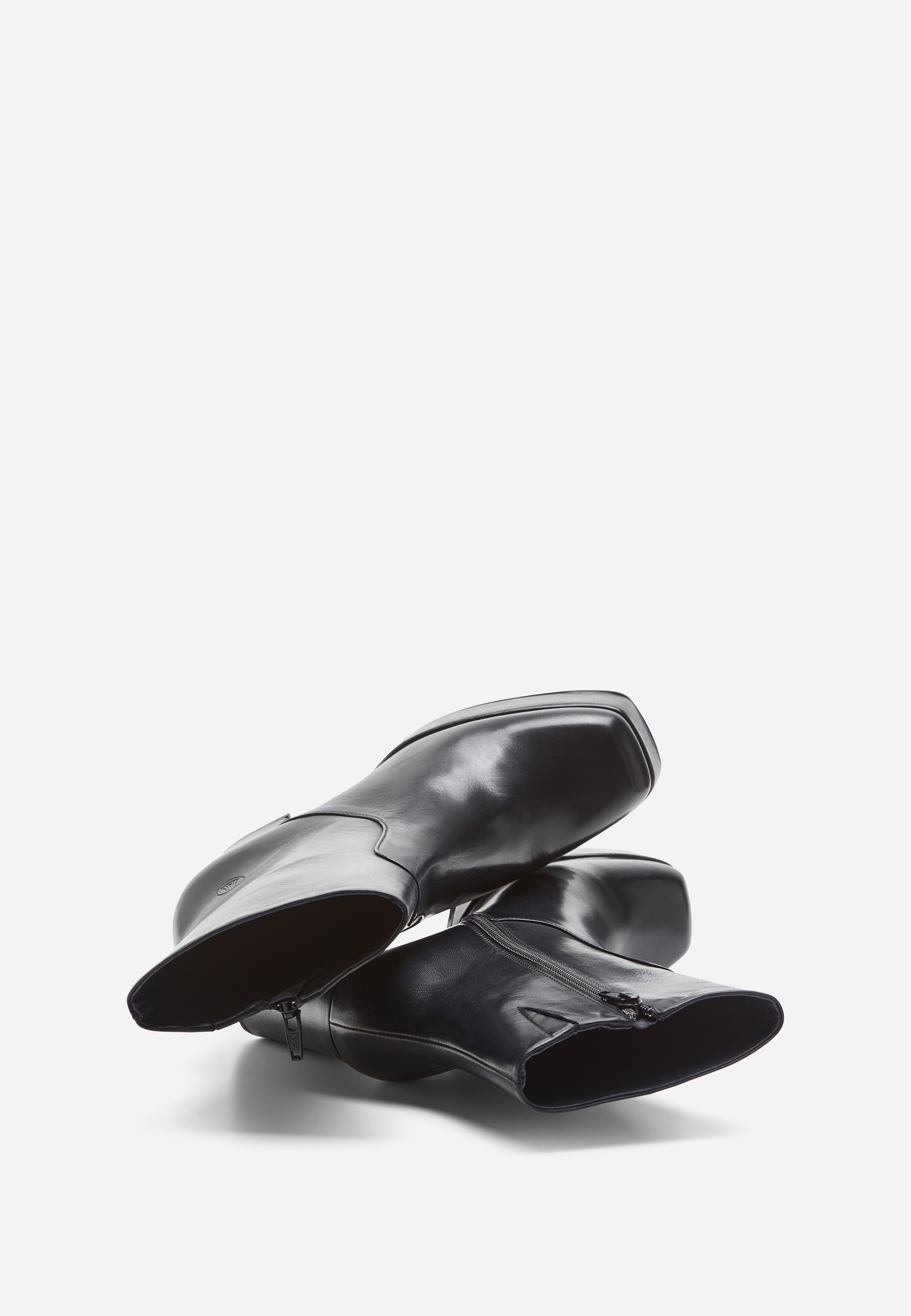 Ein Paar schwarze Lederstiefel mit quadratischen Zehen und seitlichen Reißverschlüssen, die auf der Seite vor einem schlichten weißen Hintergrund liegen.