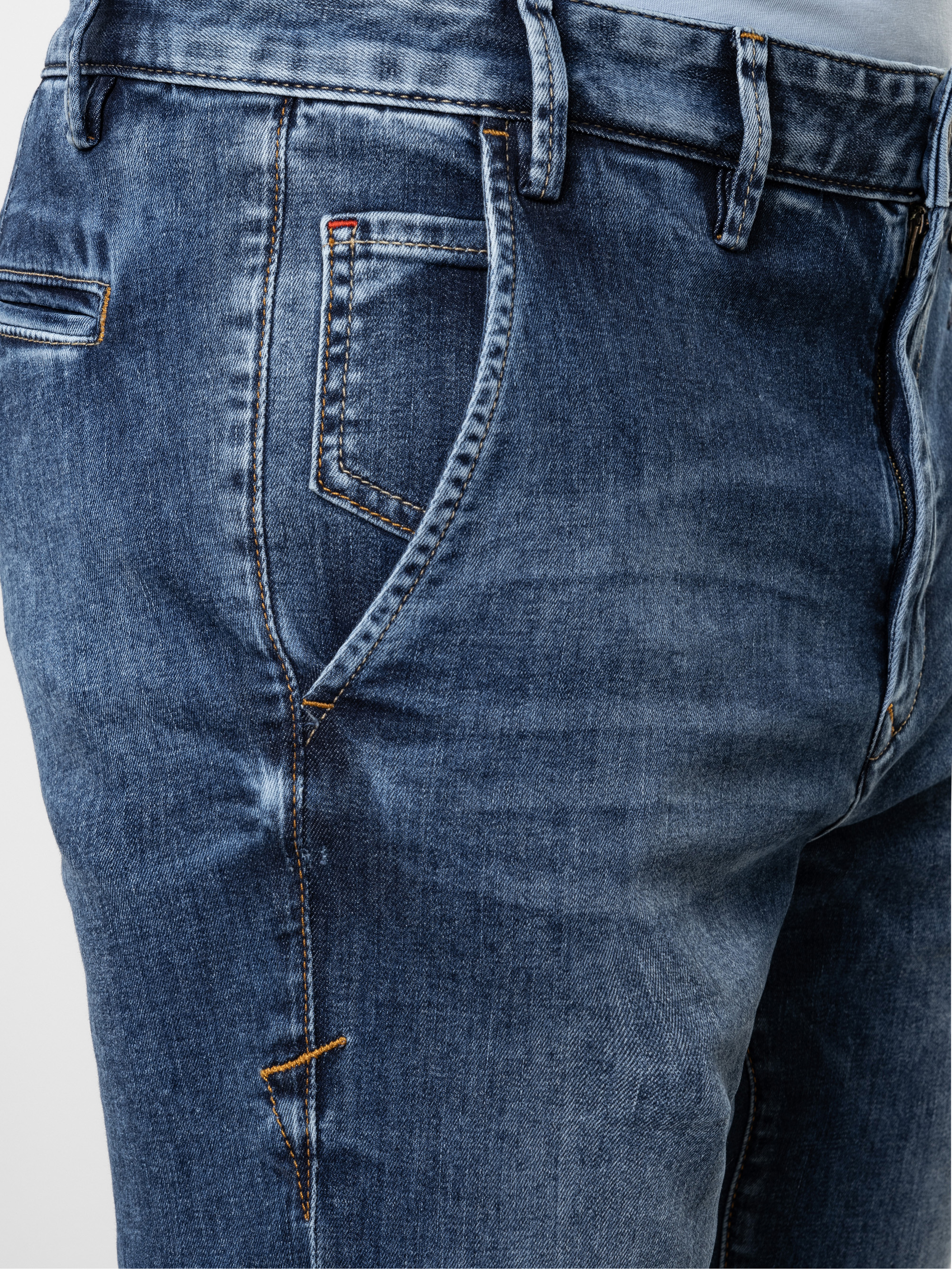 Nahaufnahme einer Person, die eine blaue Denim-Jeans trägt, mit Seitentasche, Gürtelschlaufen und Nahtdetails. Der Stoff hat eine leicht verblasste und abgenutzte Textur.