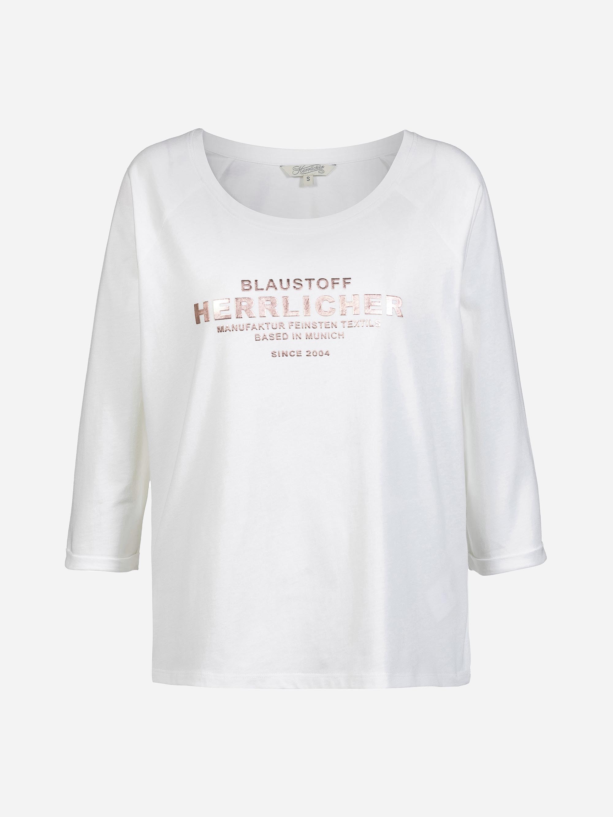 Ein weißes, dreiviertelärmeliges Damenhemd mit roségoldenem Metallic-Schriftzug auf der Vorderseite, der lautet "BLAUSTOFF HERZLICHER MANUFAKTUR FEINSTEN TEXTIL. SEIT 2004 IN MÜNCHEN ANSÄSSIG".