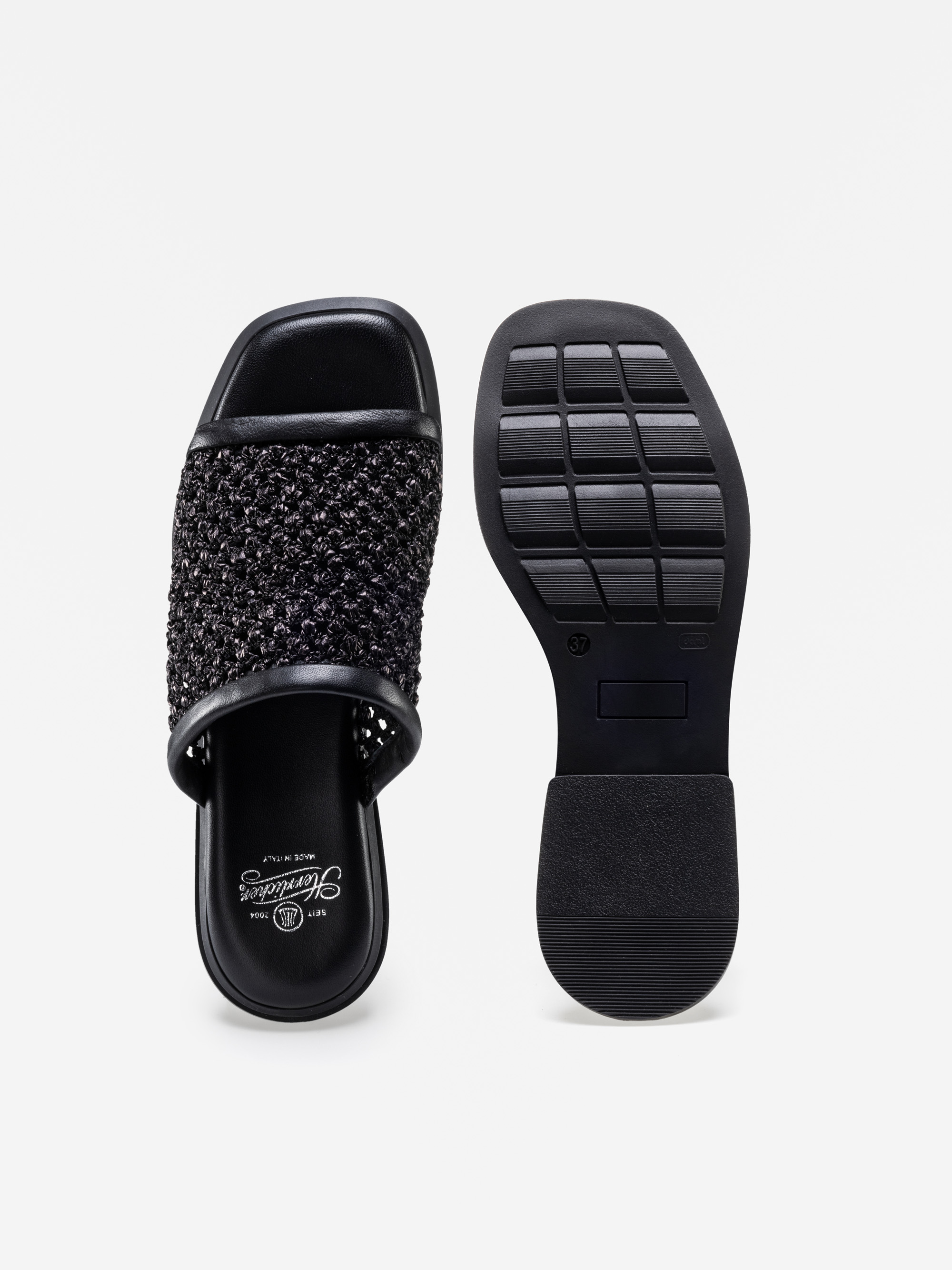 Ein Paar schwarzer gewebter Gleitsandalen; die linke Sandale zeigt das Oberteil mit einem strukturierten Riemen und einer offenen Spitze, während die rechte Sandale die Sohle mit einem quadratischen Muster für den Halt zeigt.