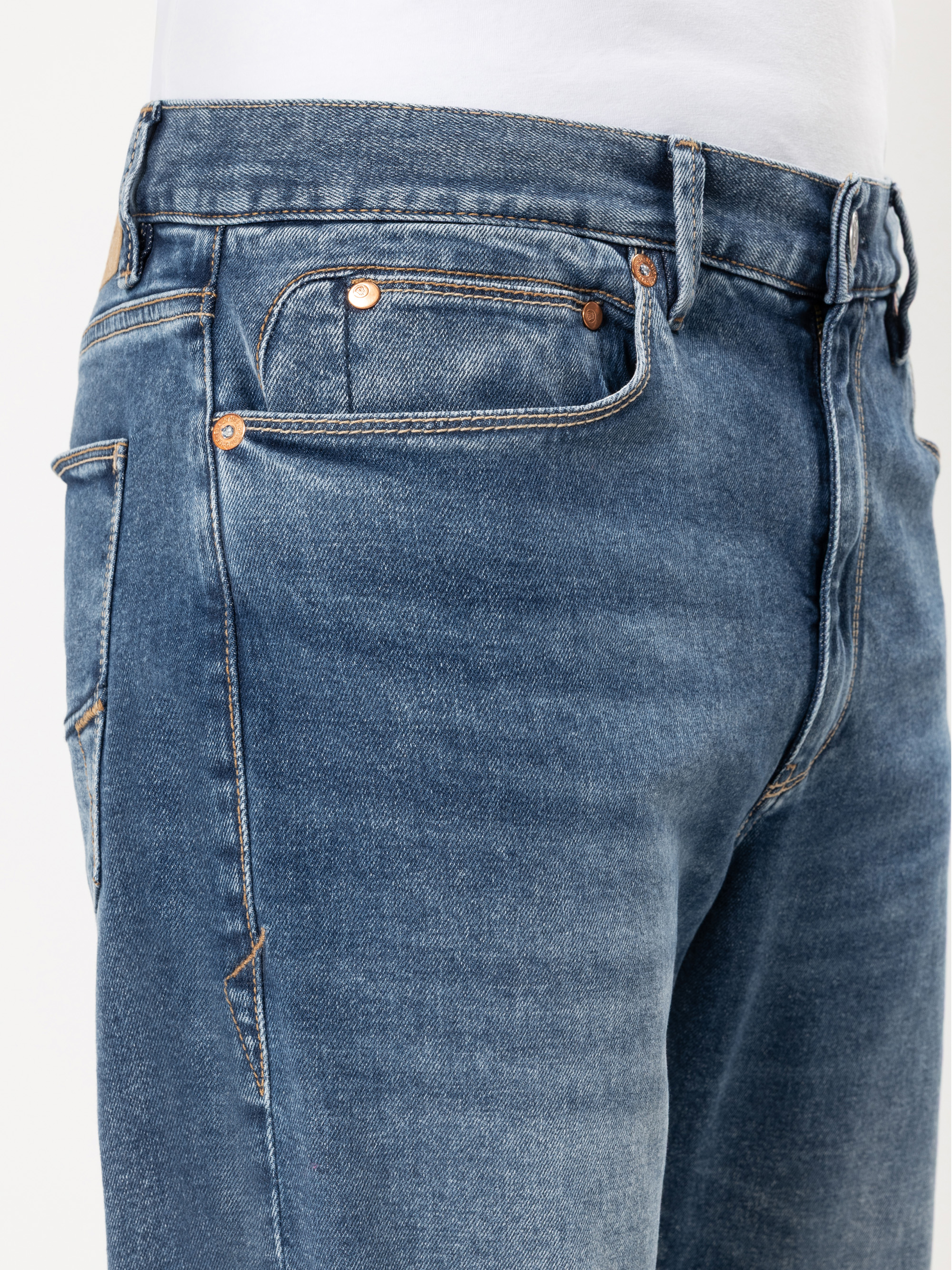 Nahaufnahme einer Person, die eine blaue Jeans und ein weißes Hemd trägt, wobei der Schwerpunkt auf der vorderen Tasche und dem Bundbereich liegt.