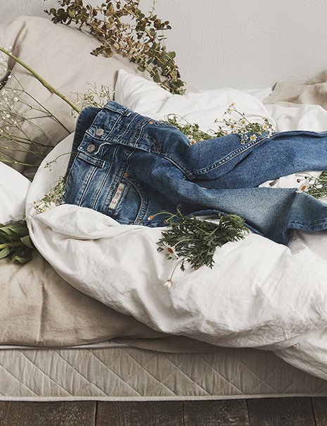 Blaue Herrlicher Jeans auf Bett liegend mit Blumen